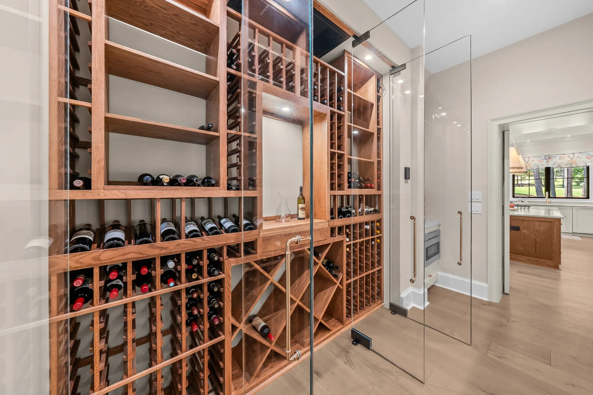 Custom glass-enclosed wine room by FRS Homes featuring handcrafted wood wine storage, floor-to-ceiling bottle racks, and a temperature-controlled display for luxury entertaining.
