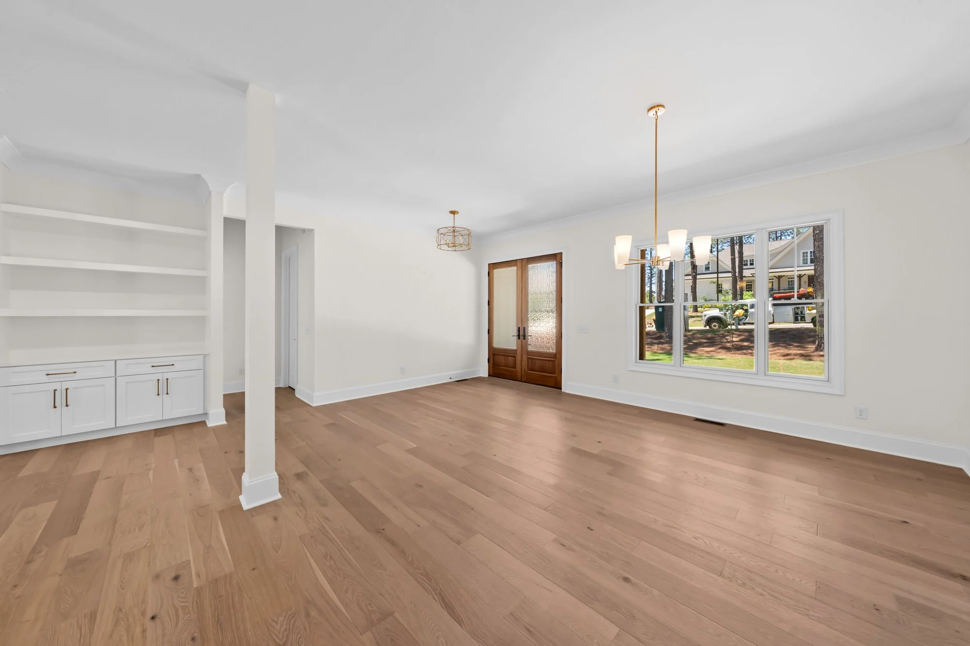 Flexible living space by FRS Homes featuring custom built-in shelving, wood double entry doors, and an open floor plan for a home office, media room, or family retreat.