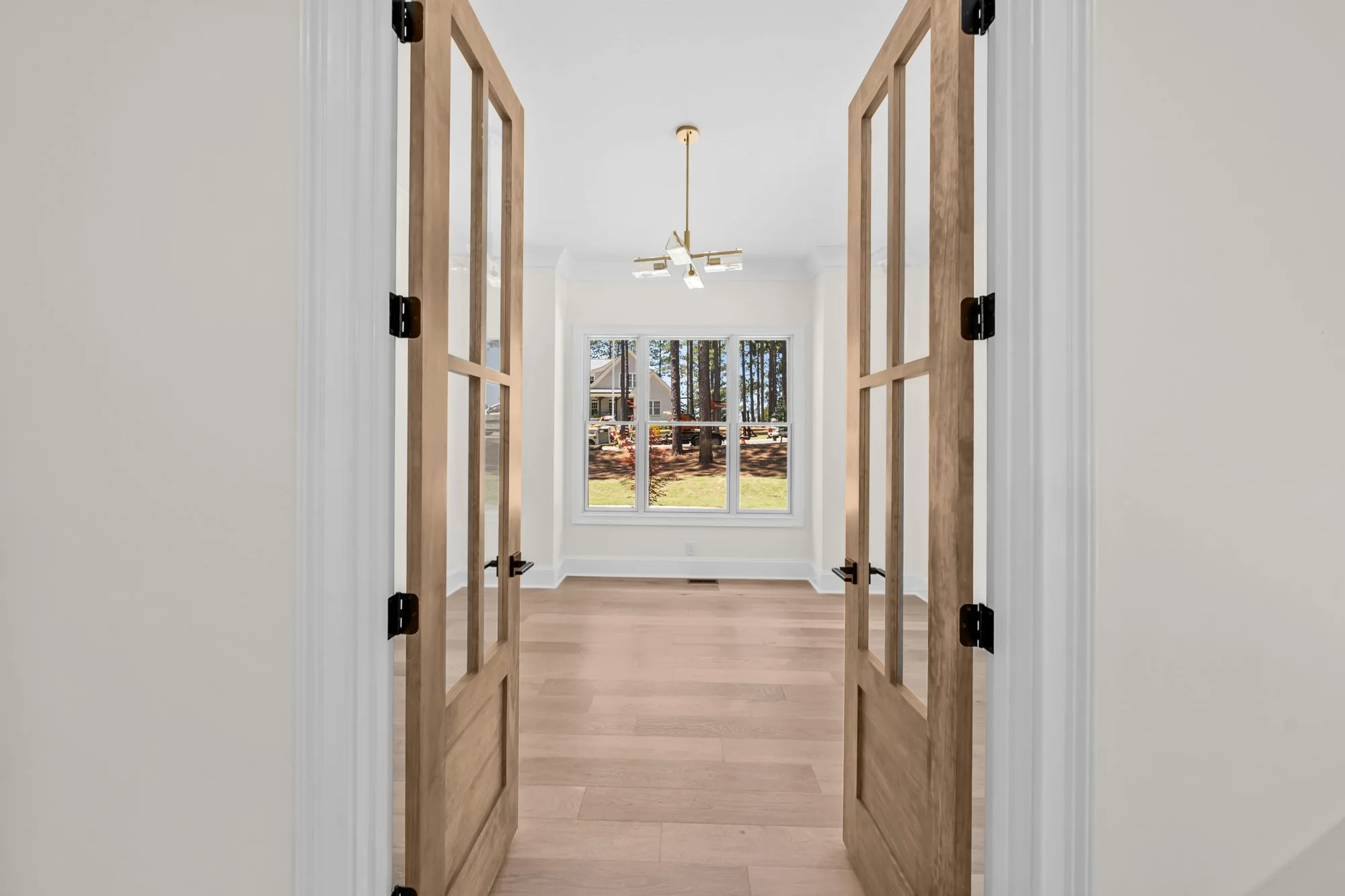 Private home office by FRS Homes featuring natural wood French doors, large windows, and an open layout designed for productivity and natural light.