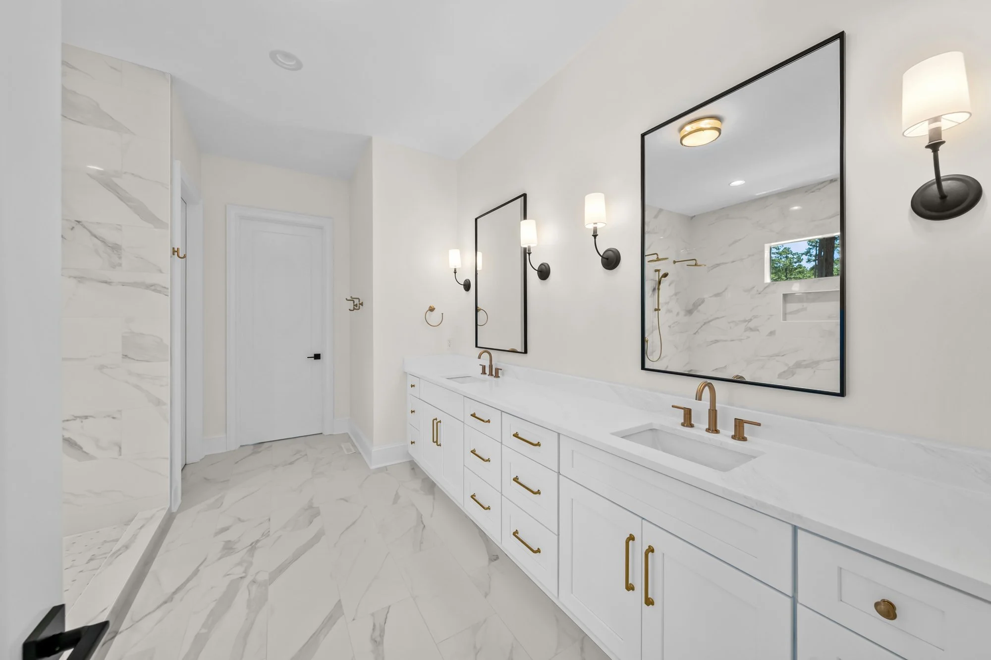 Luxury primary bathroom by FRS Homes featuring a double vanity with quartz countertops, marble-look tile flooring, matte black mirrors, and brushed brass fixtures.