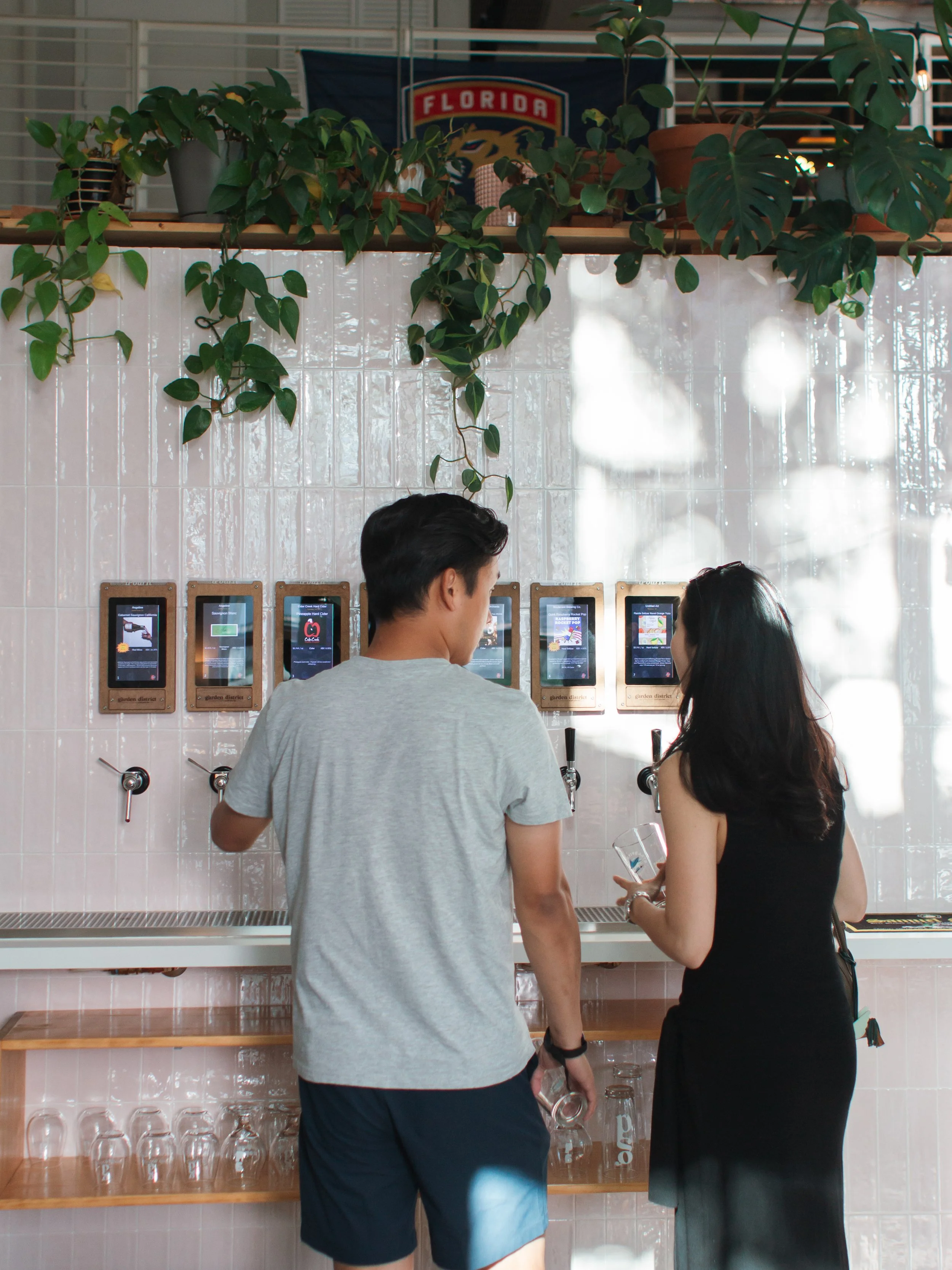 young couple looking at the tap wall at garden district taproom in west palm beach, fl.