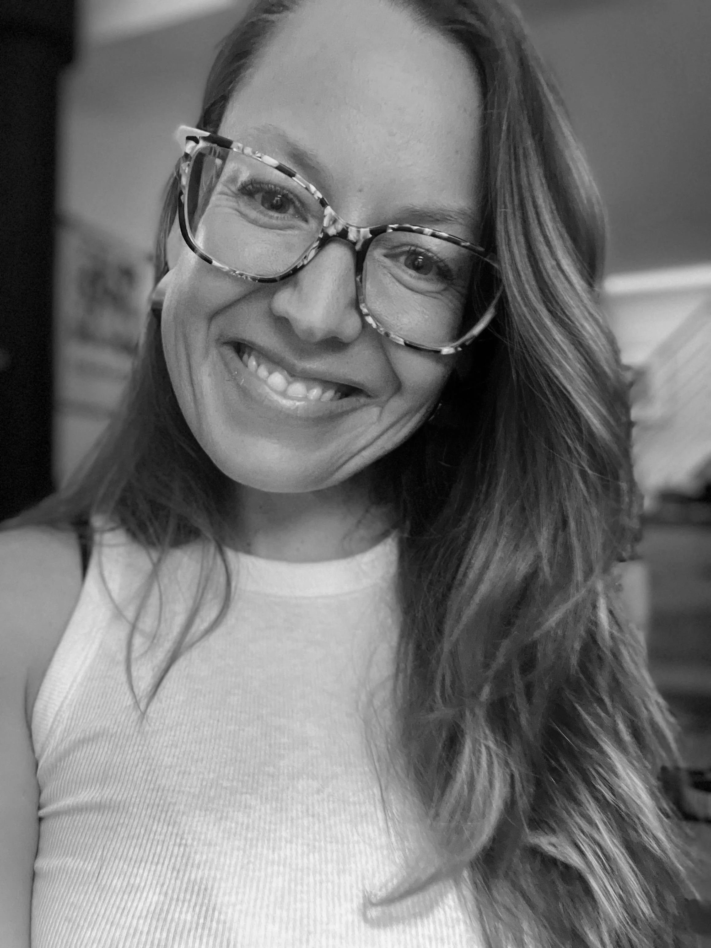Person wearing a hat, glasses, and scarf in a black and white image.