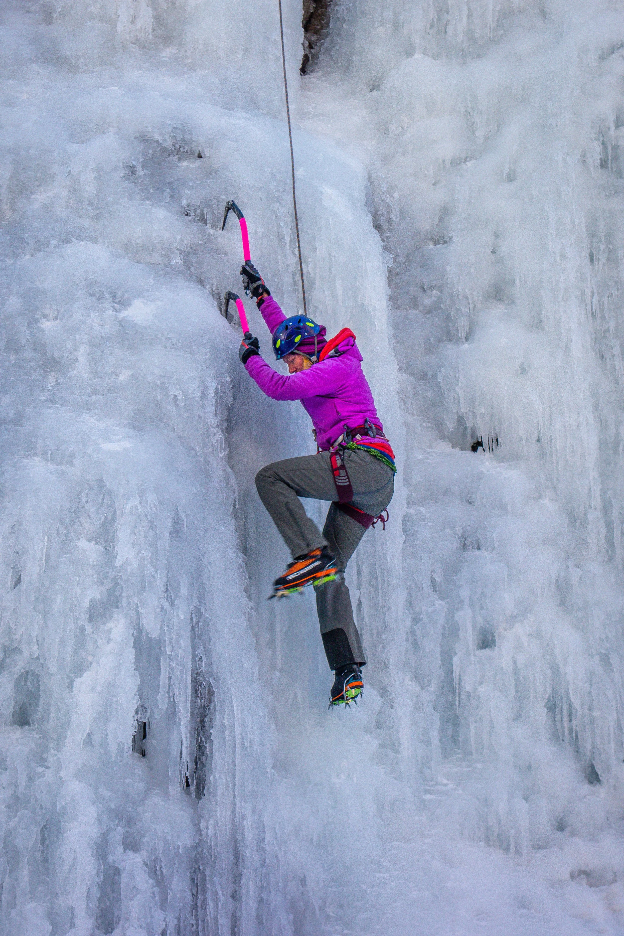 women in pink patagonia jacket learning ice climbing from a climbing guide