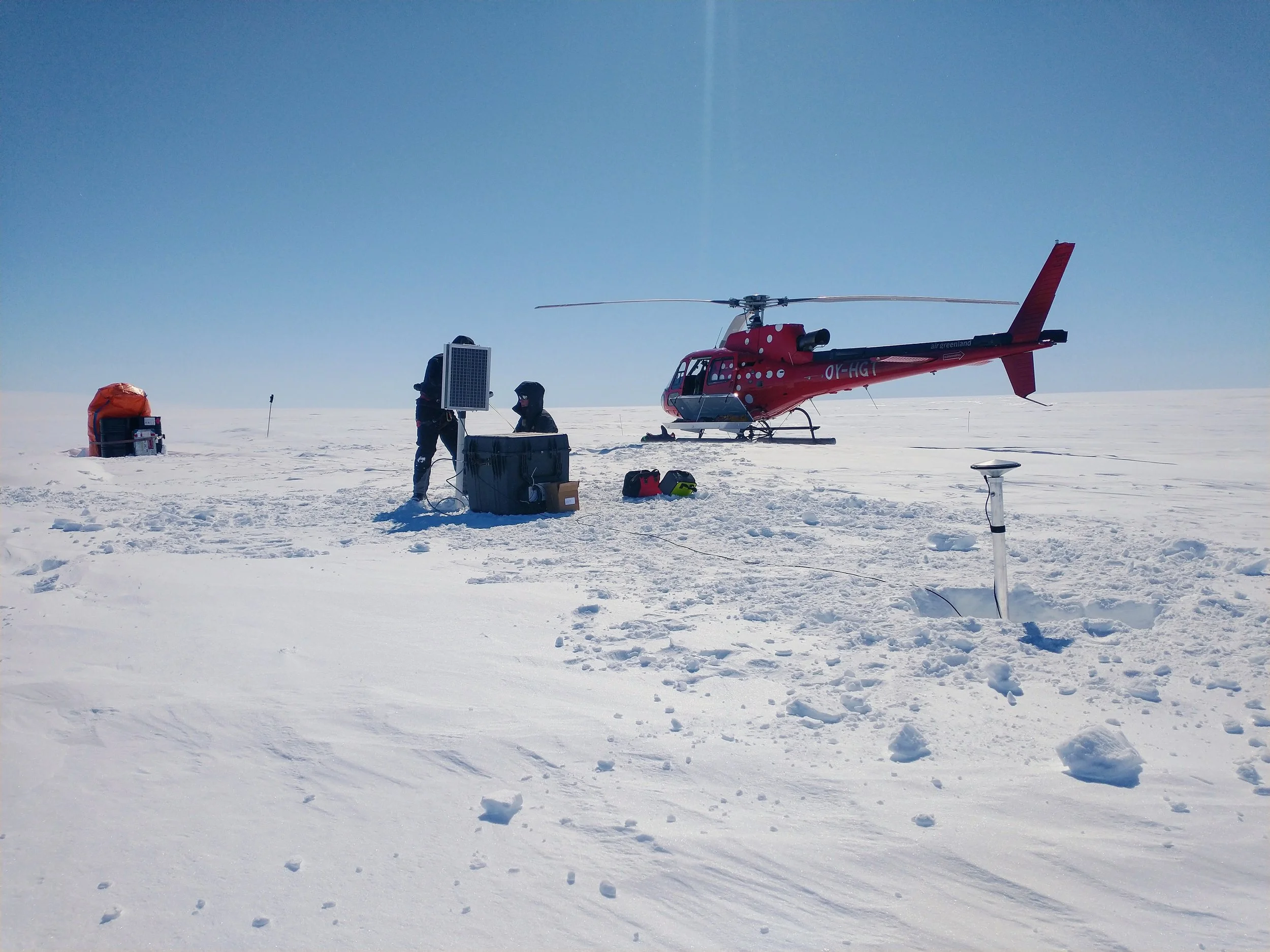 a helicopter and researchers installing research equipment on the Greenland Ice Field
