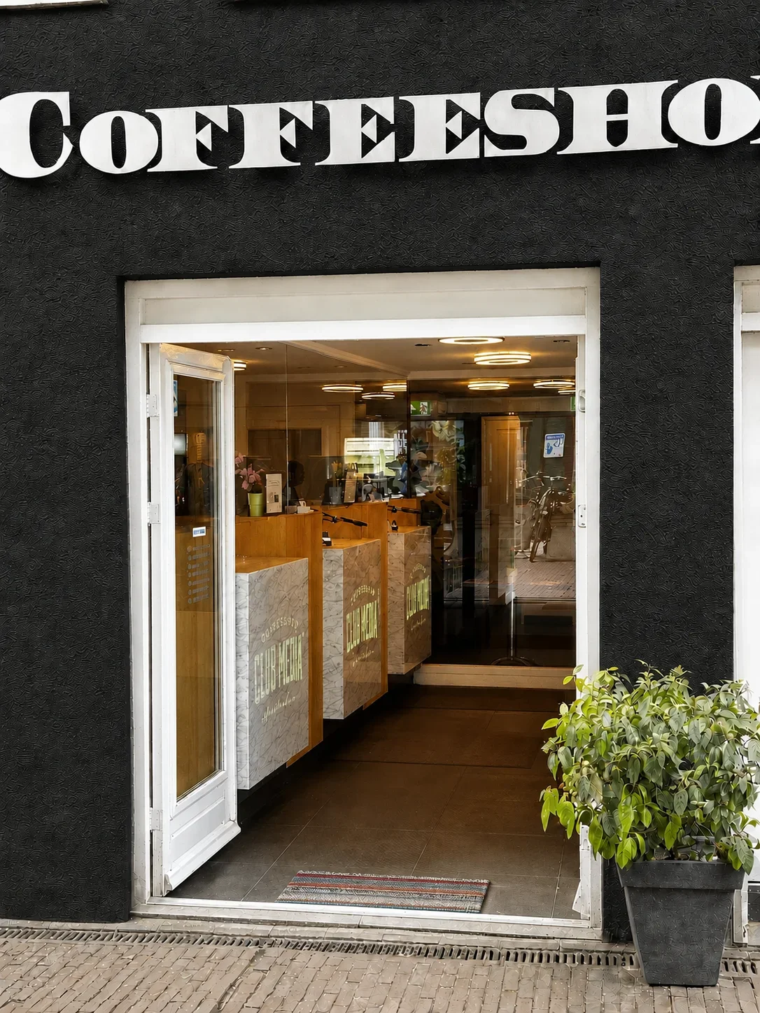 De ingang van Club Media aan de Gerard Doustraat, omgeven door groene planten