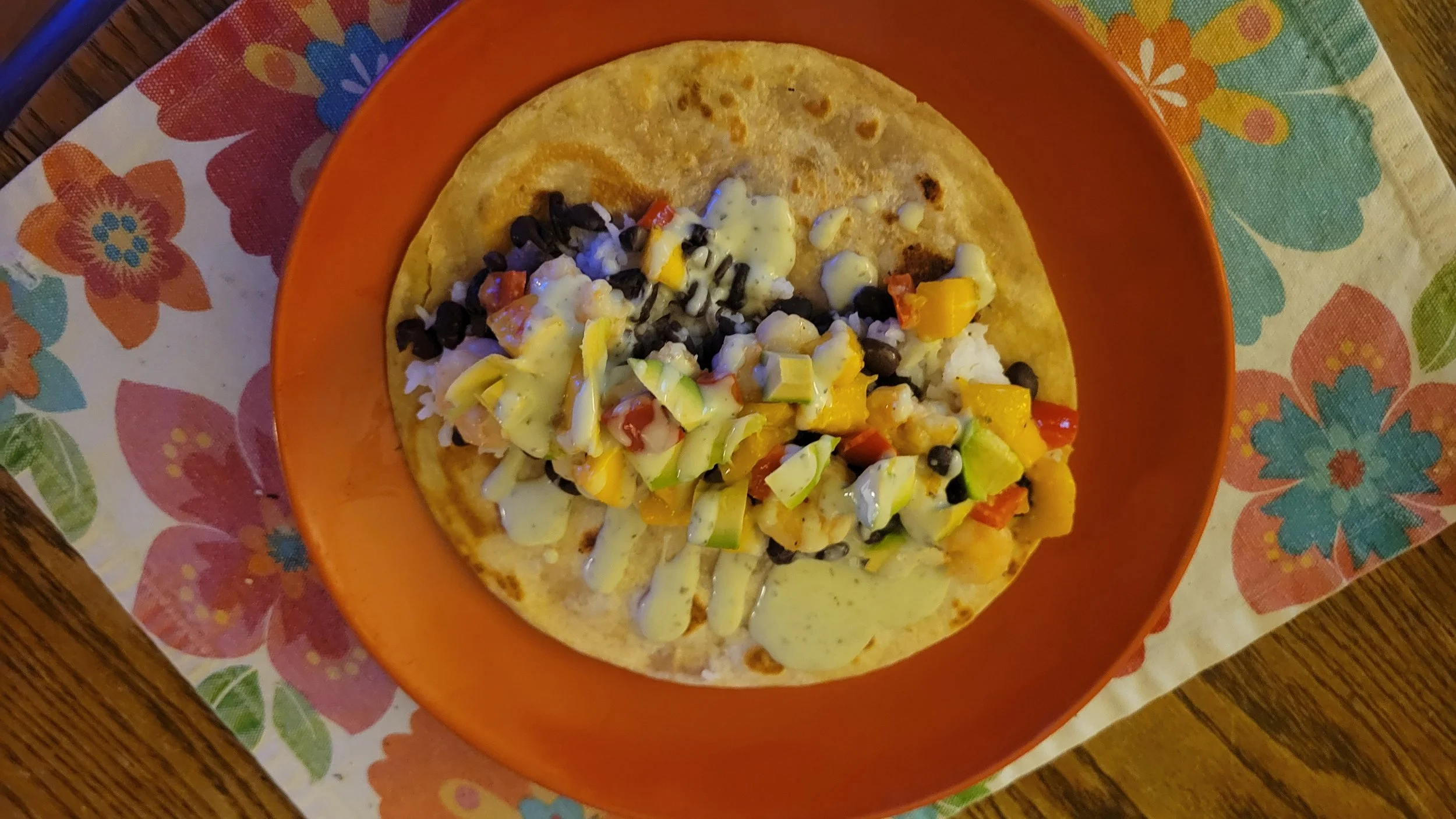 Mango-lime shrimp burrito on an orange plate with a multicolor placemat