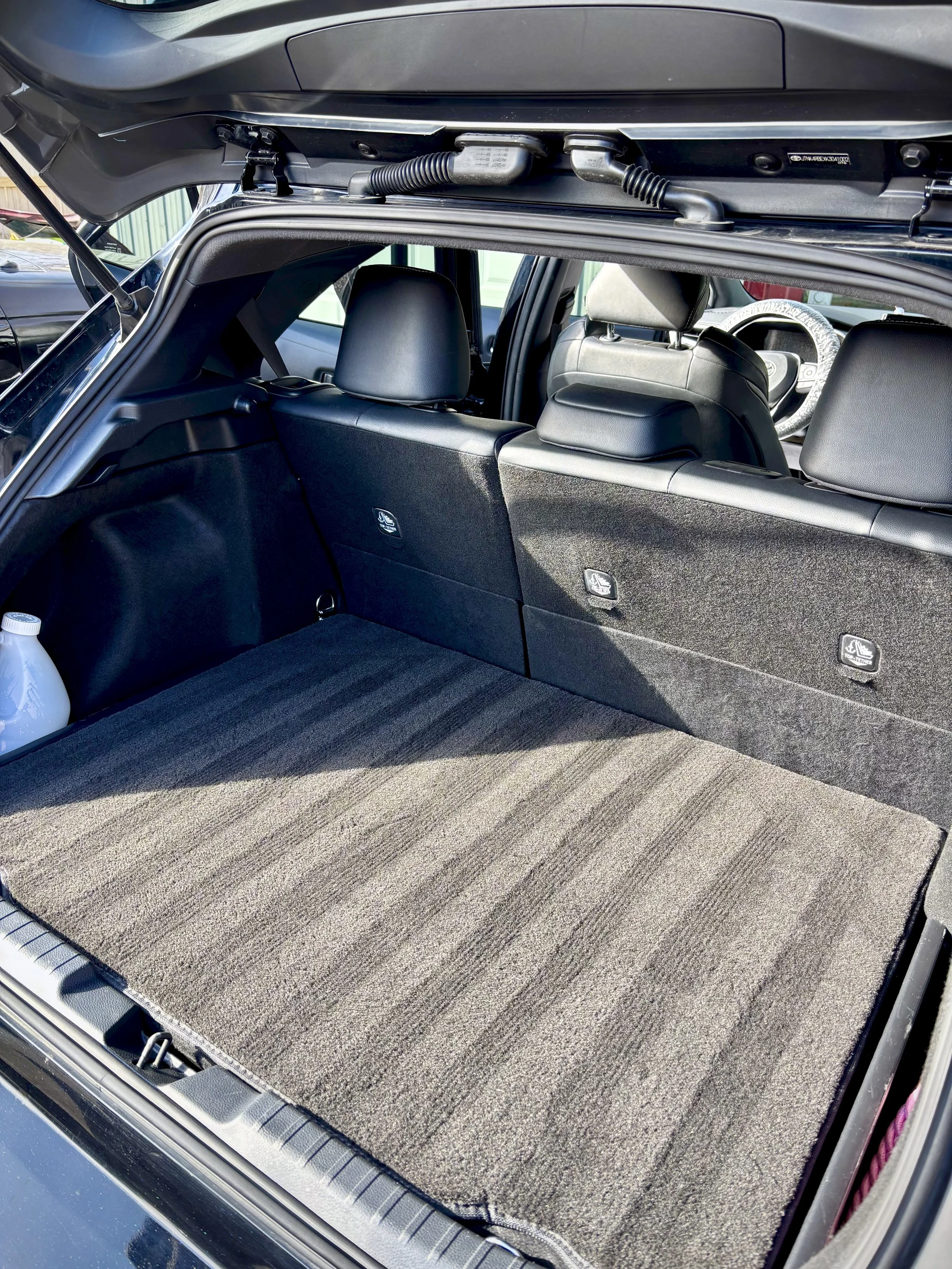 View of the open trunk of a vehicle with a spacious, carpeted cargo area and the back of the rear seats.