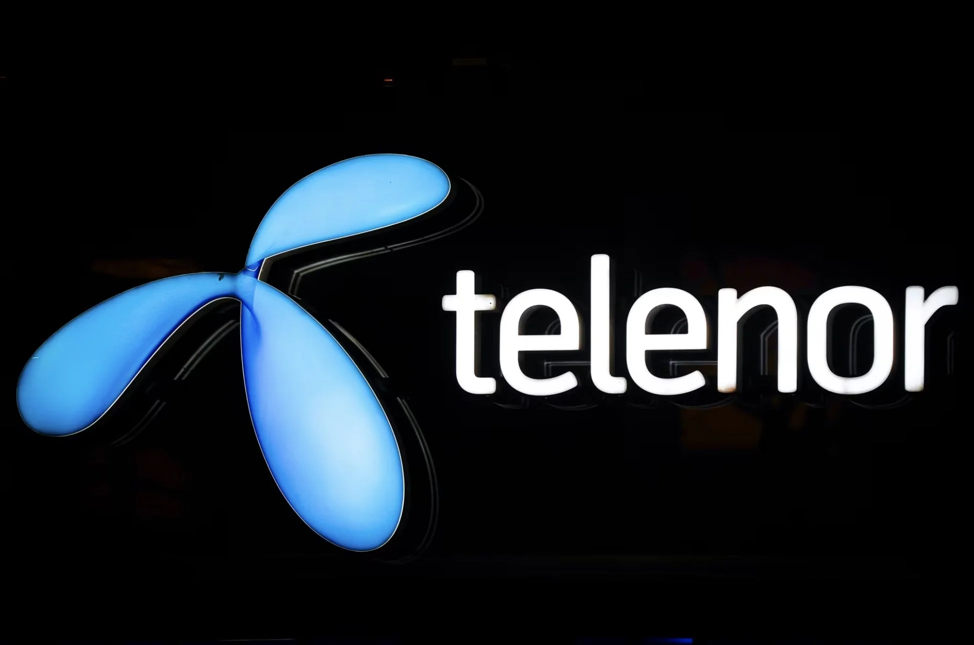 Telenor, logo med hvit tekst og blått symbol mot svart bakgrunn.
