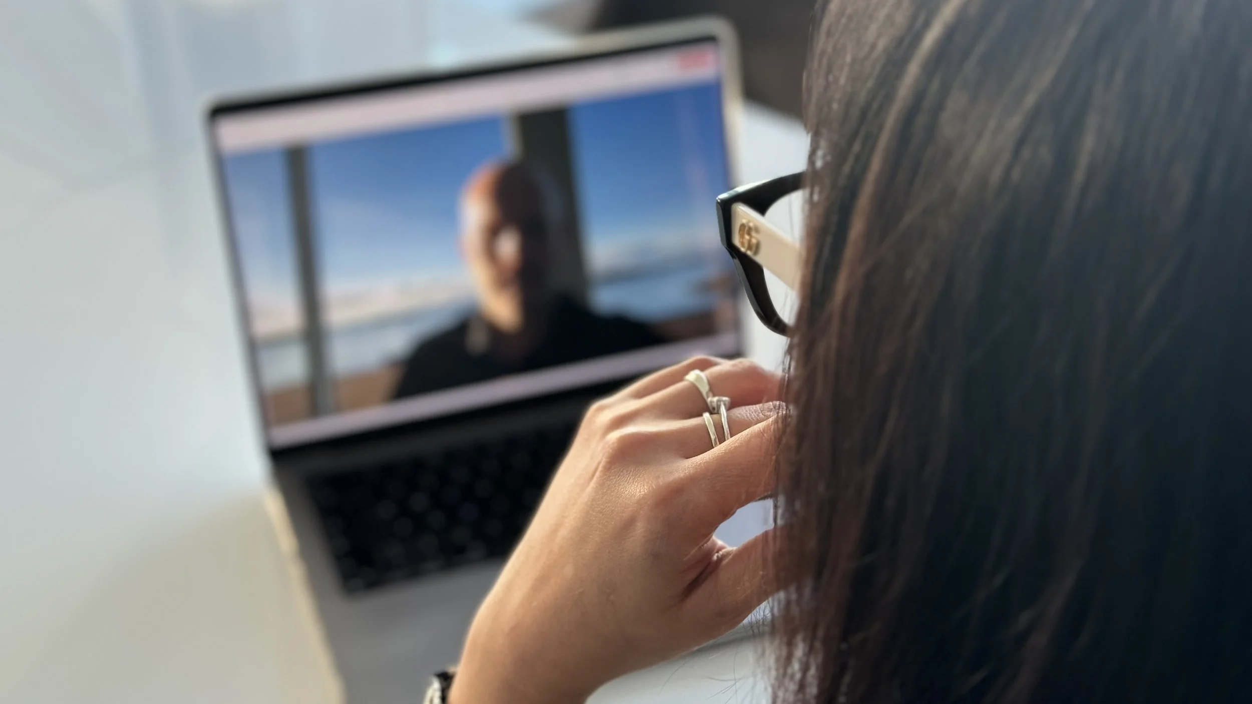 En kvinne sitter foran en laptop og deltar i et videomøte med en privat etterforsker fra Privatgranskeren AS, som vises på skjermen med utsikt i bakgrunnen.