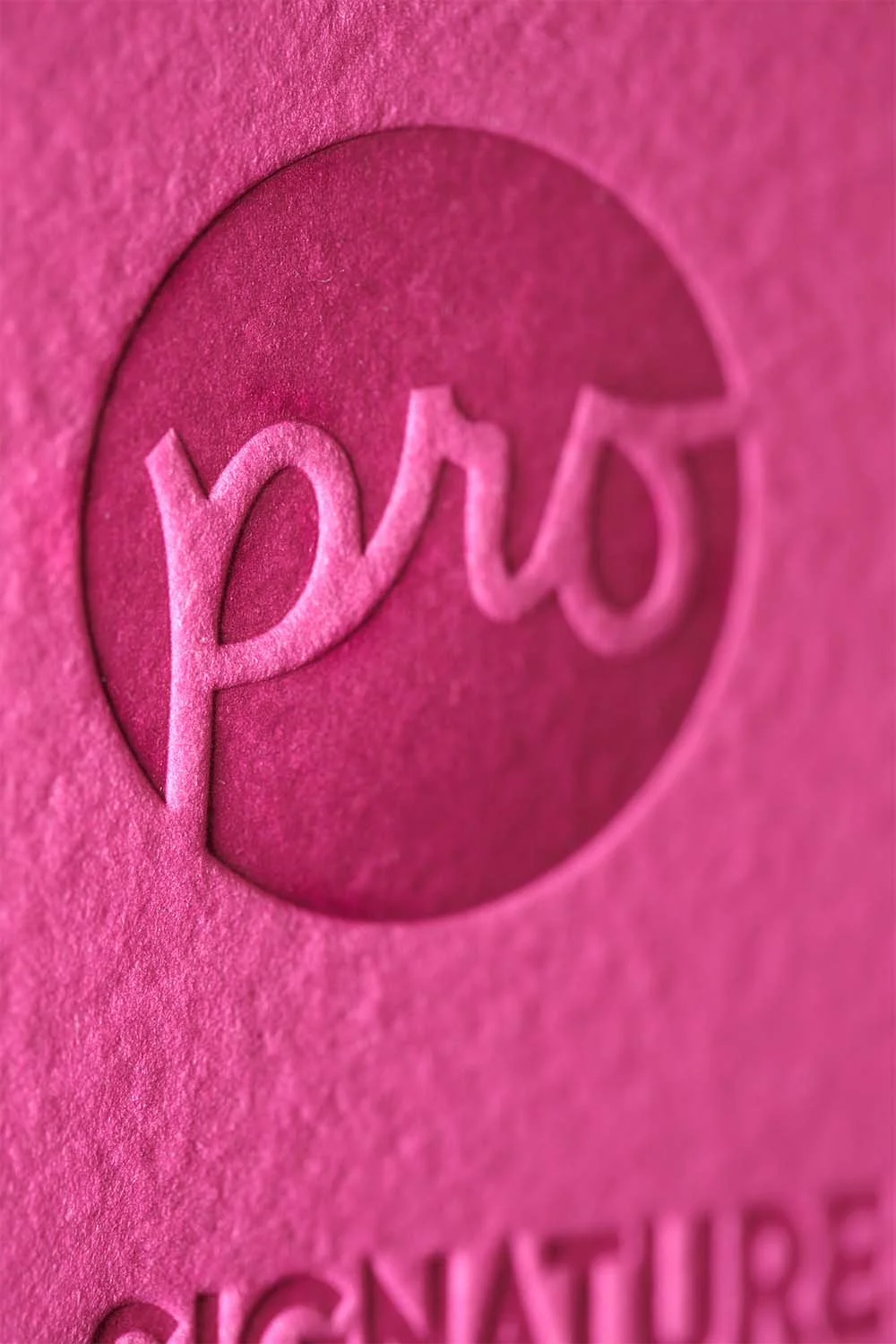 Macro detail of embossed logo on textured pink paper featuring tactile luxury event signage and layered design elements.