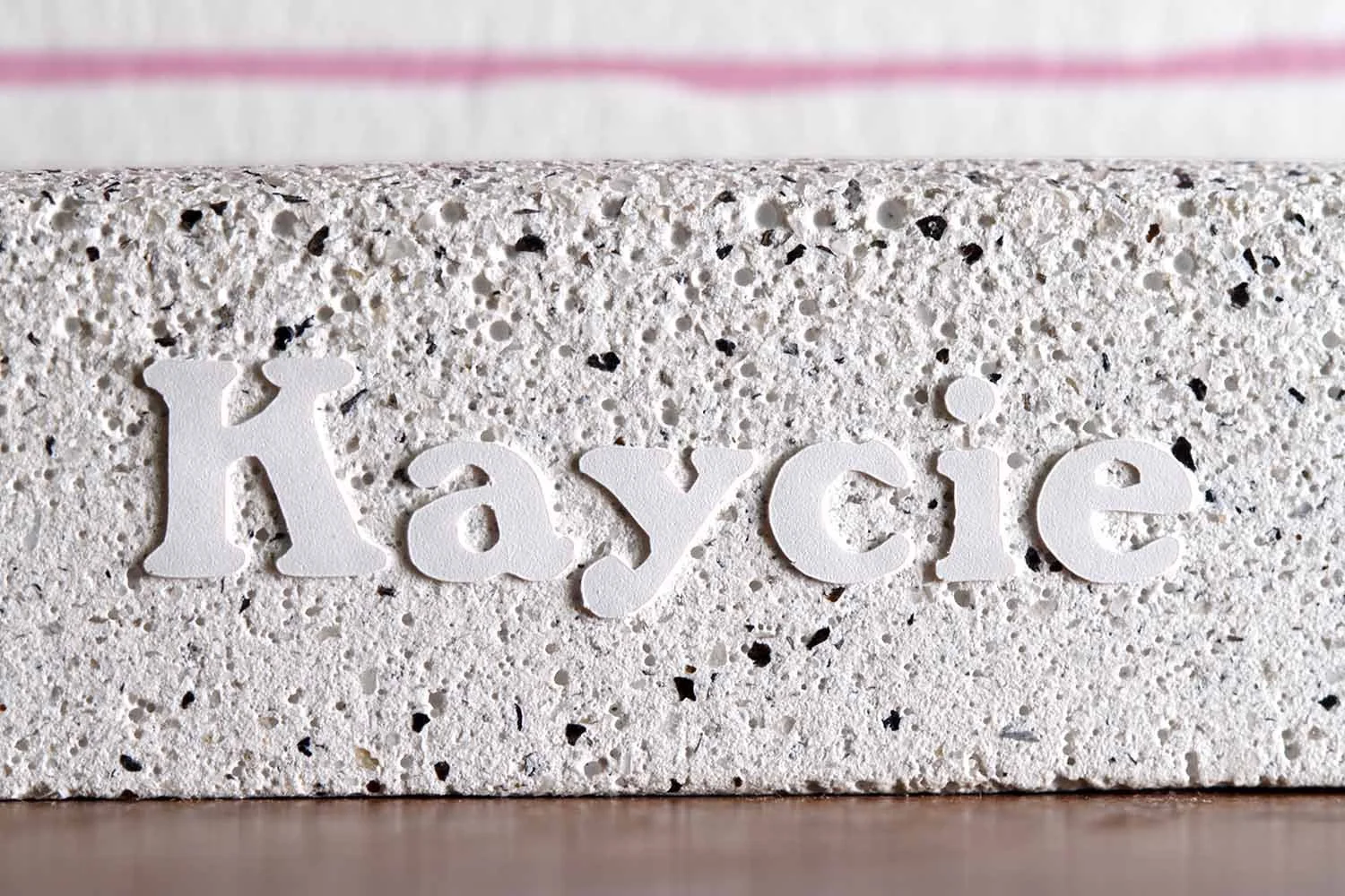 Close-up of a textured stone-inspired wedding menu holder with dimensional name lettering, paired with custom day-of wedding stationery.