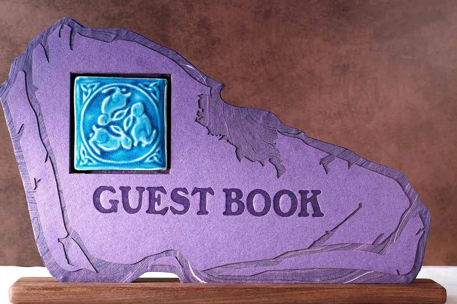 Custom wedding guest book sign with layered paper textures, artisan ceramic tile inset, and walnut display base designed for a luxury wedding reception.