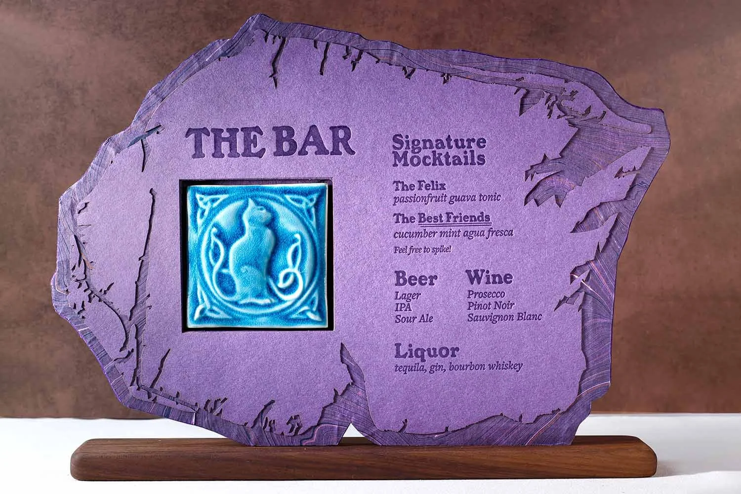 Custom wedding bar sign with letterpress printing, layered marble paper details, handcrafted ceramic tile artwork, and a walnut display base.