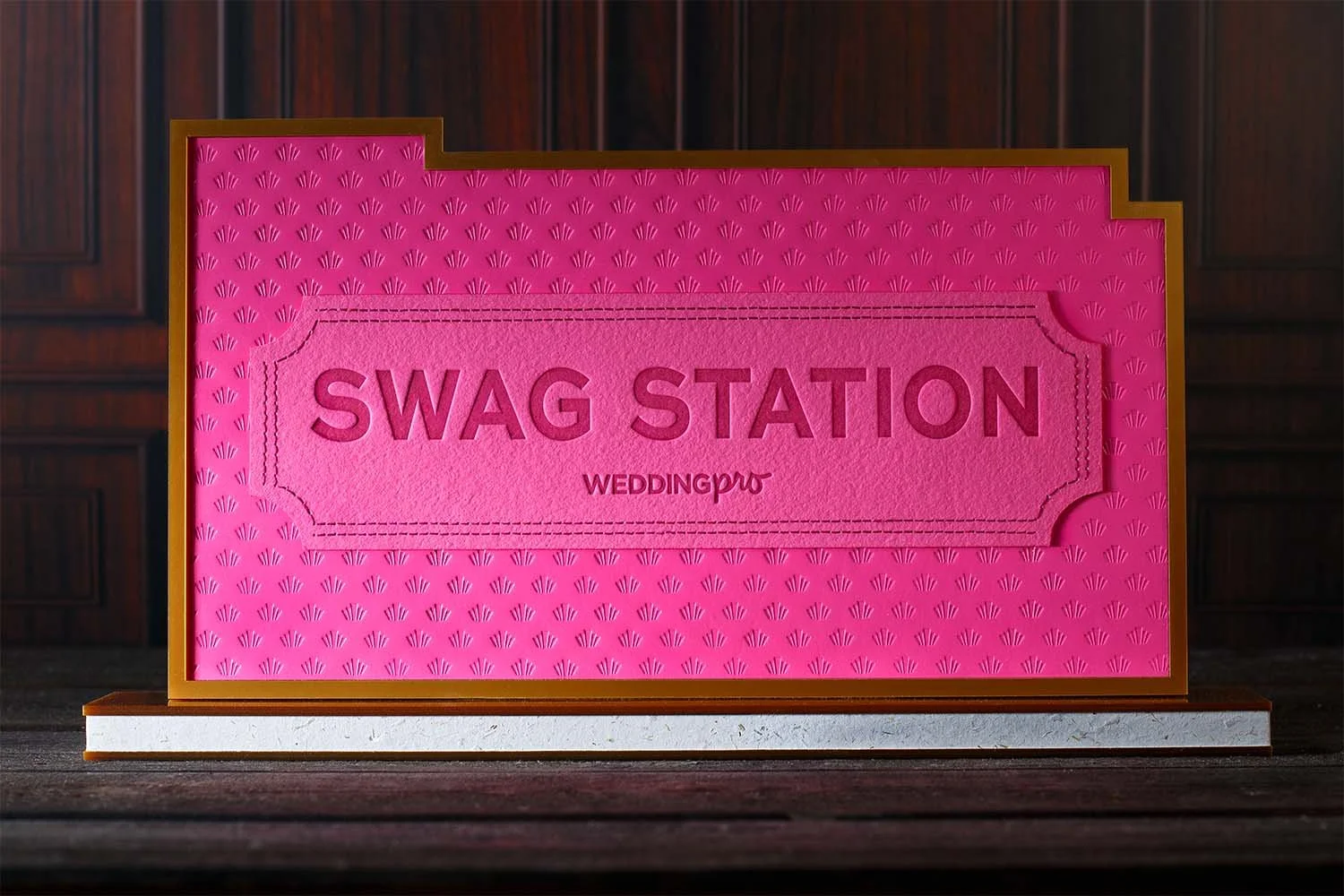 Custom Art Deco swag station sign with embossed pink ticket design, layered acrylic details, and luxury event branding by Lucasano Creative.