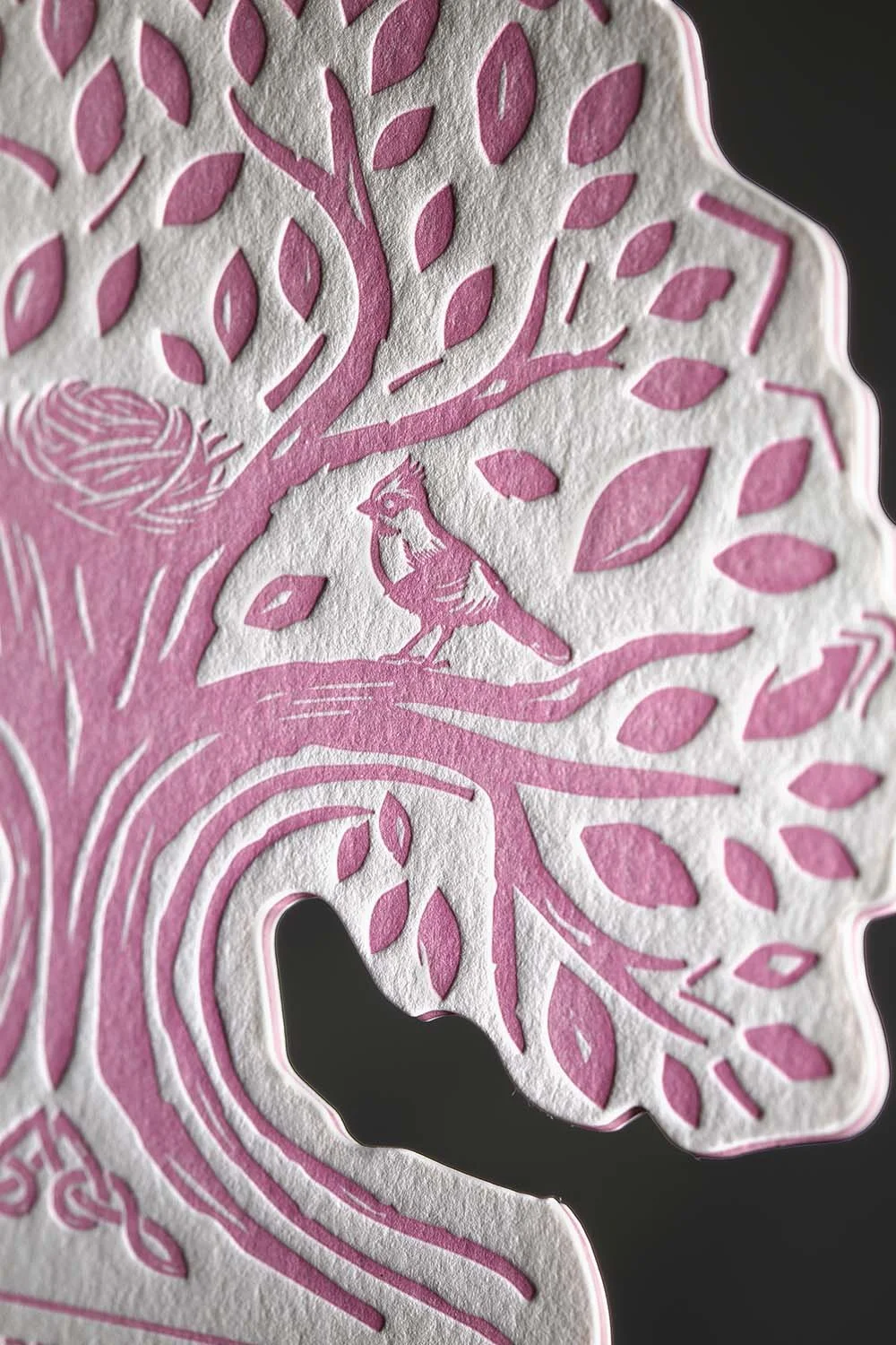 Close-up of a die-cut tree wedding menu with letterpress printing, intricate bird illustrations, and layered cotton paper construction.