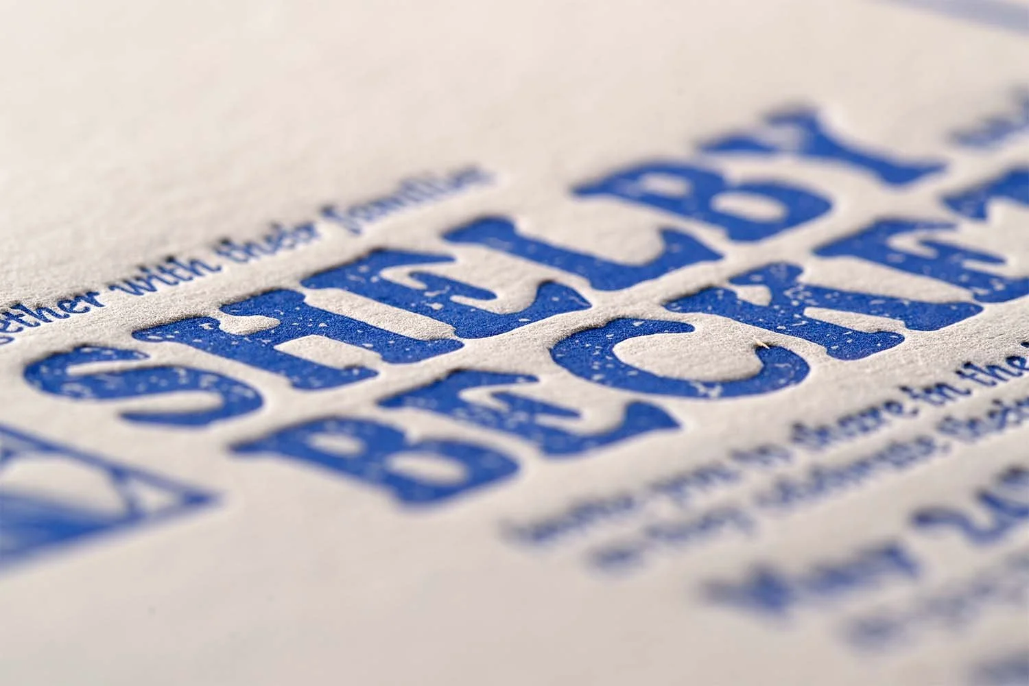 Macro detail of blue letterpress wedding invitation typography printed on soft textured cotton paper.
