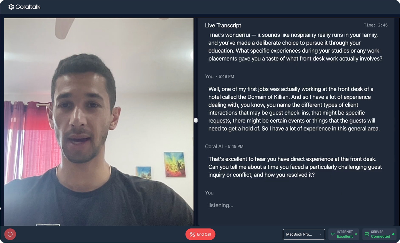 A young man with short dark hair and a light beard, wearing a black shirt, is on a video call in a room with pink curtains and colorful artwork on the walls.