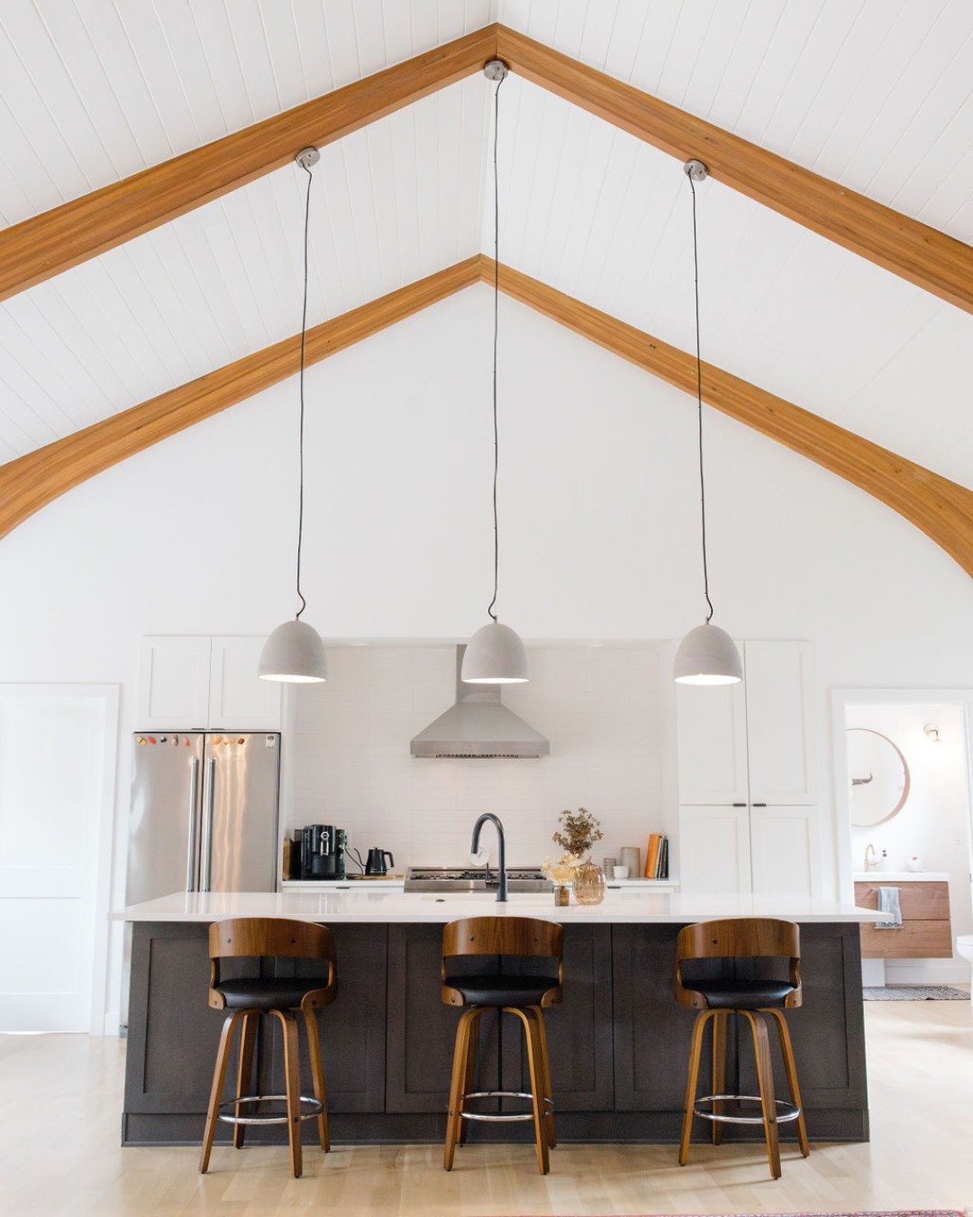 Warm tones and minimalist elegance meet in this stunning open kitchen, perfect for upcoming holiday entertaining.⁣
⁣
The sleek pendant lights draw attention to the vaulted ceiling&rsquo;s natural wood beams, creating a seamless blend of modern and ru