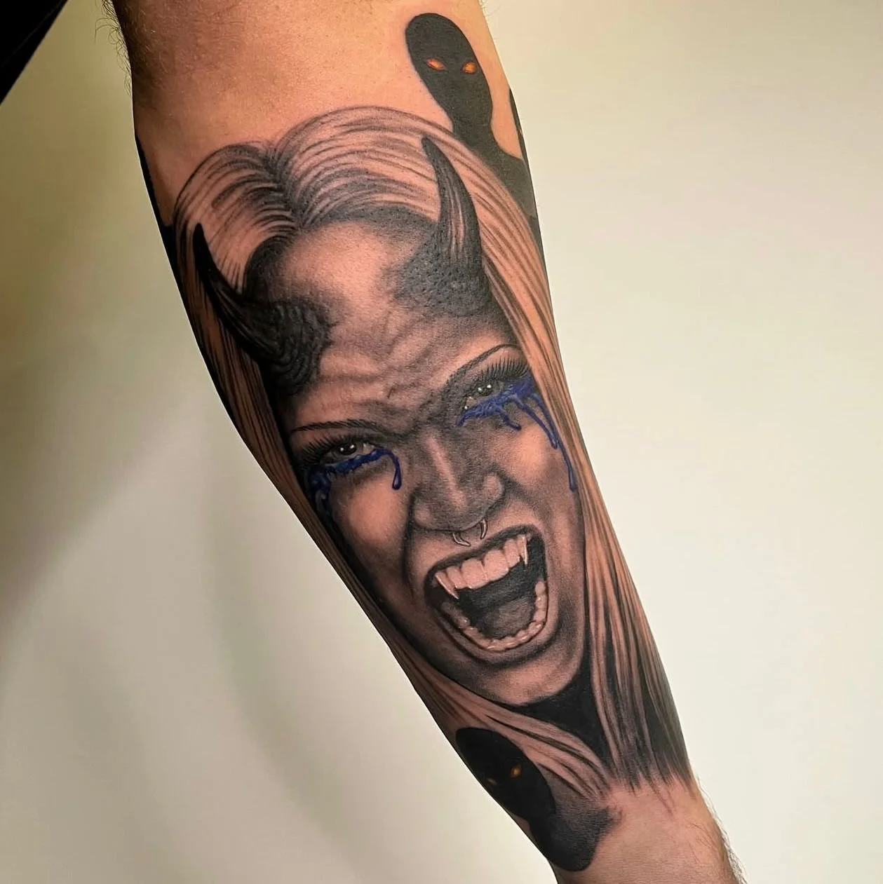 Dark black and grey illustrative realism portrait depicting a demon lady with horns, screaming with fangs, and crying blue tears. With shadow people with red eyes surrounding her behind her.