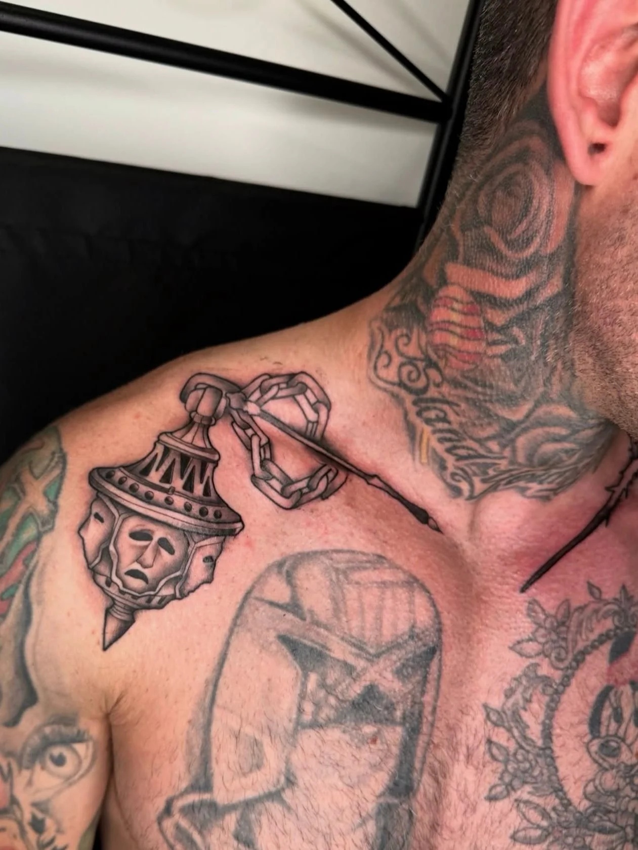 Black and grey bold tattoo on the collarbone of a flail weapon, Veredicto from the video game Blasphemous 2.