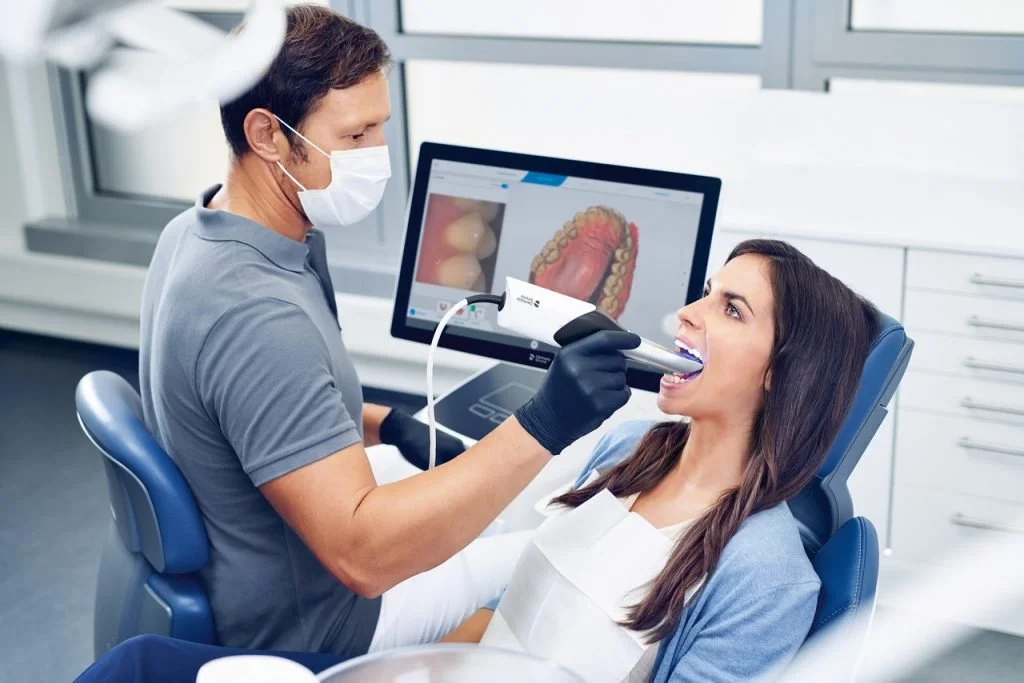 Dentist performing a dental checkup using an intraoral scanner on a woman patient in a dental office.