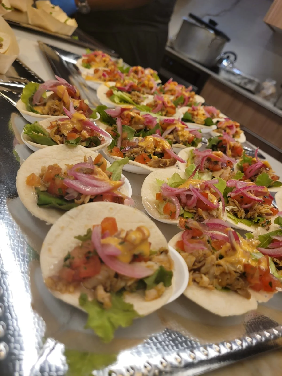 Mini tacos with toppings on a silver tray