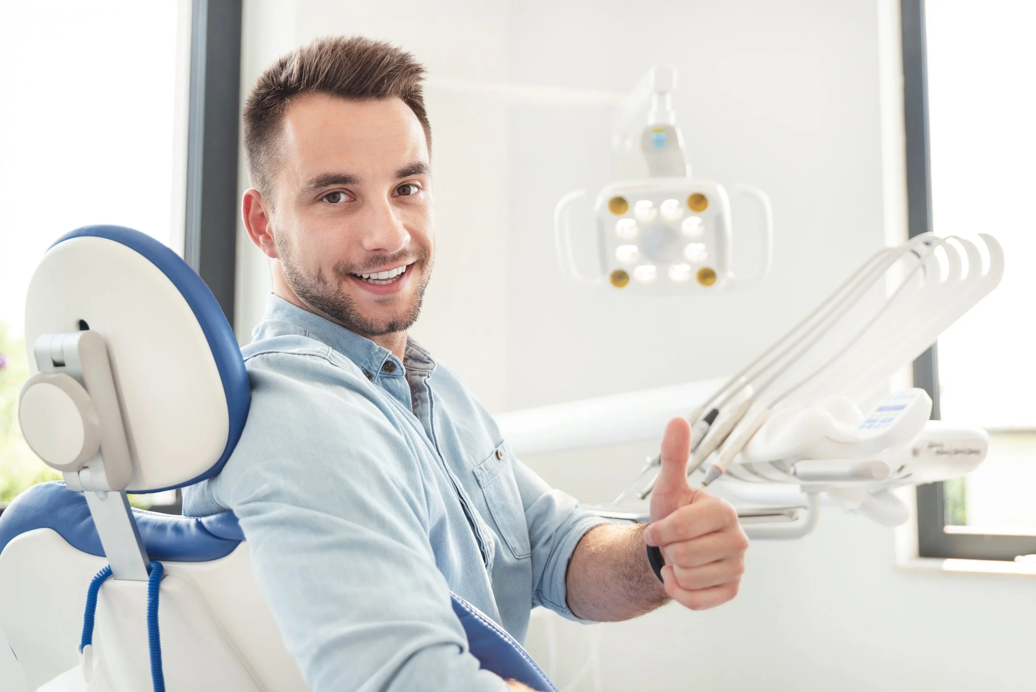 Close-up of a smiling man making a heart shape with his hands at a dental appointment.
