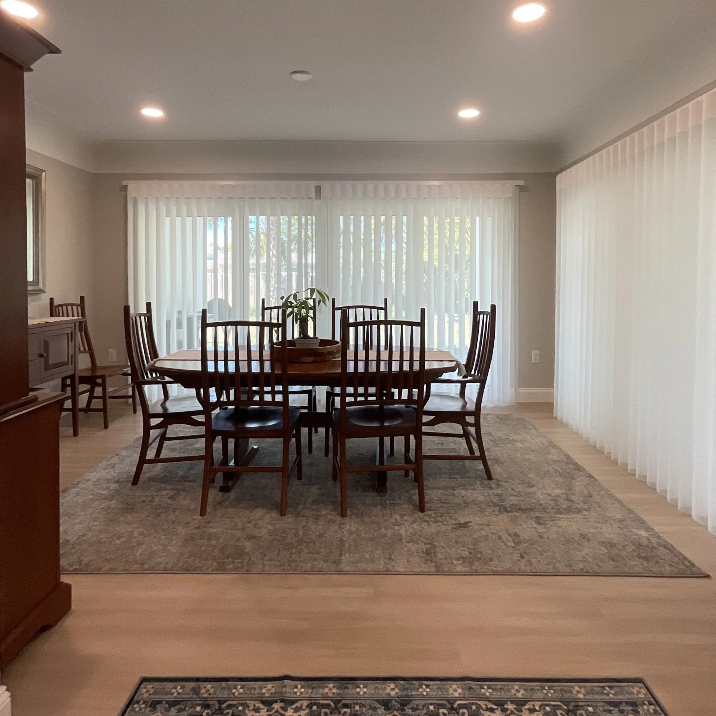 Dining room with sliding glass doors on two sides opening to lanai and future pool, featuring modern table and chairs.