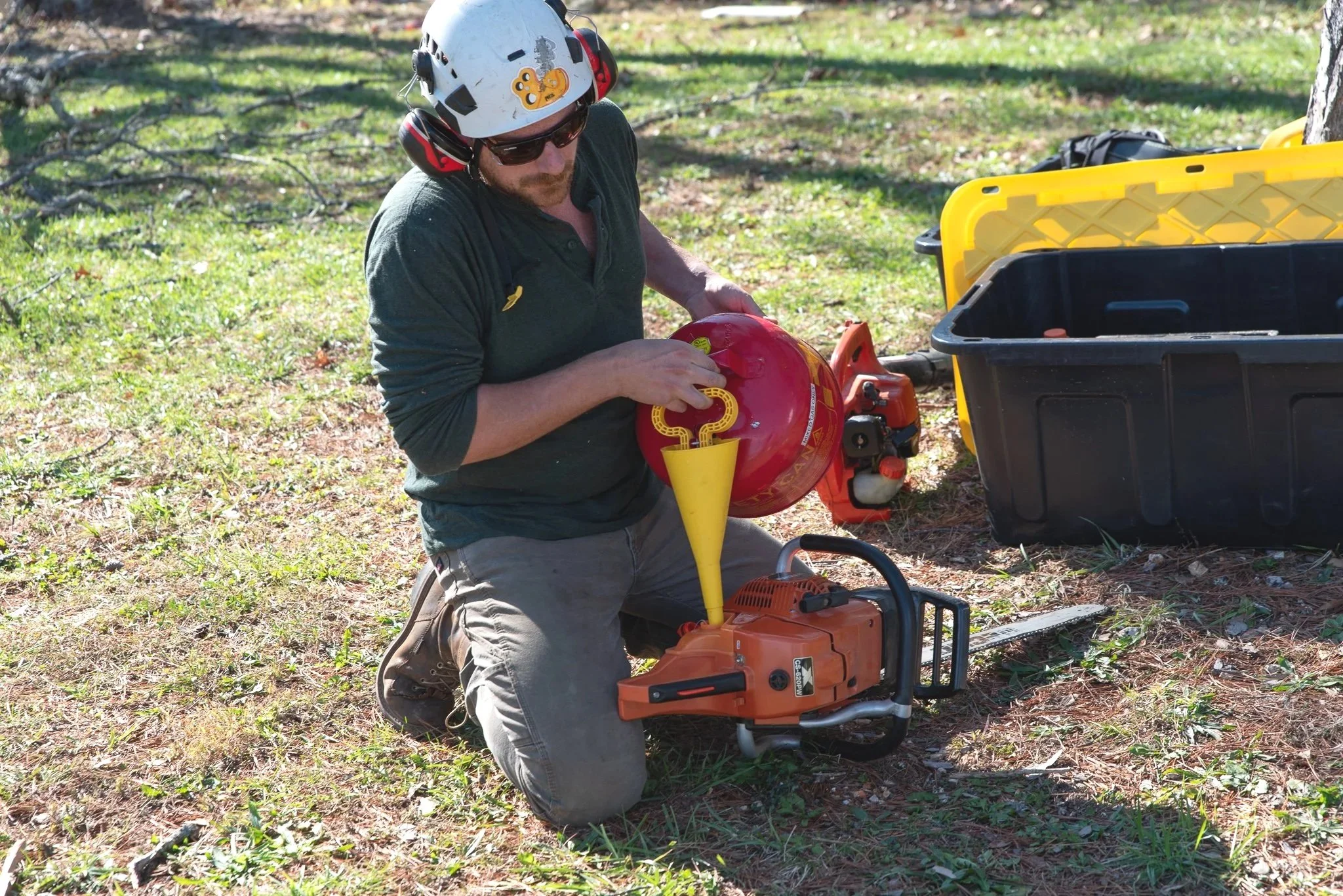 a man about to cut down a tree. filling his chainsaw with gas and oil