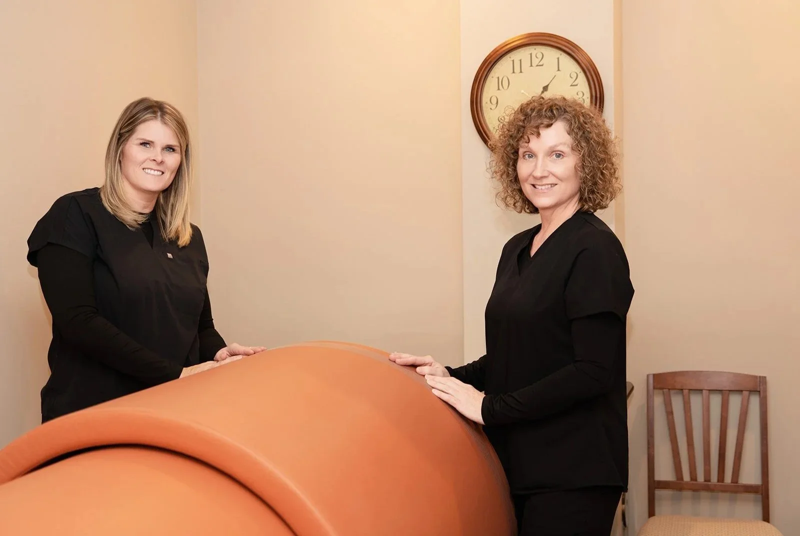 Two women standing at a whole body hyperthermia sauna dome