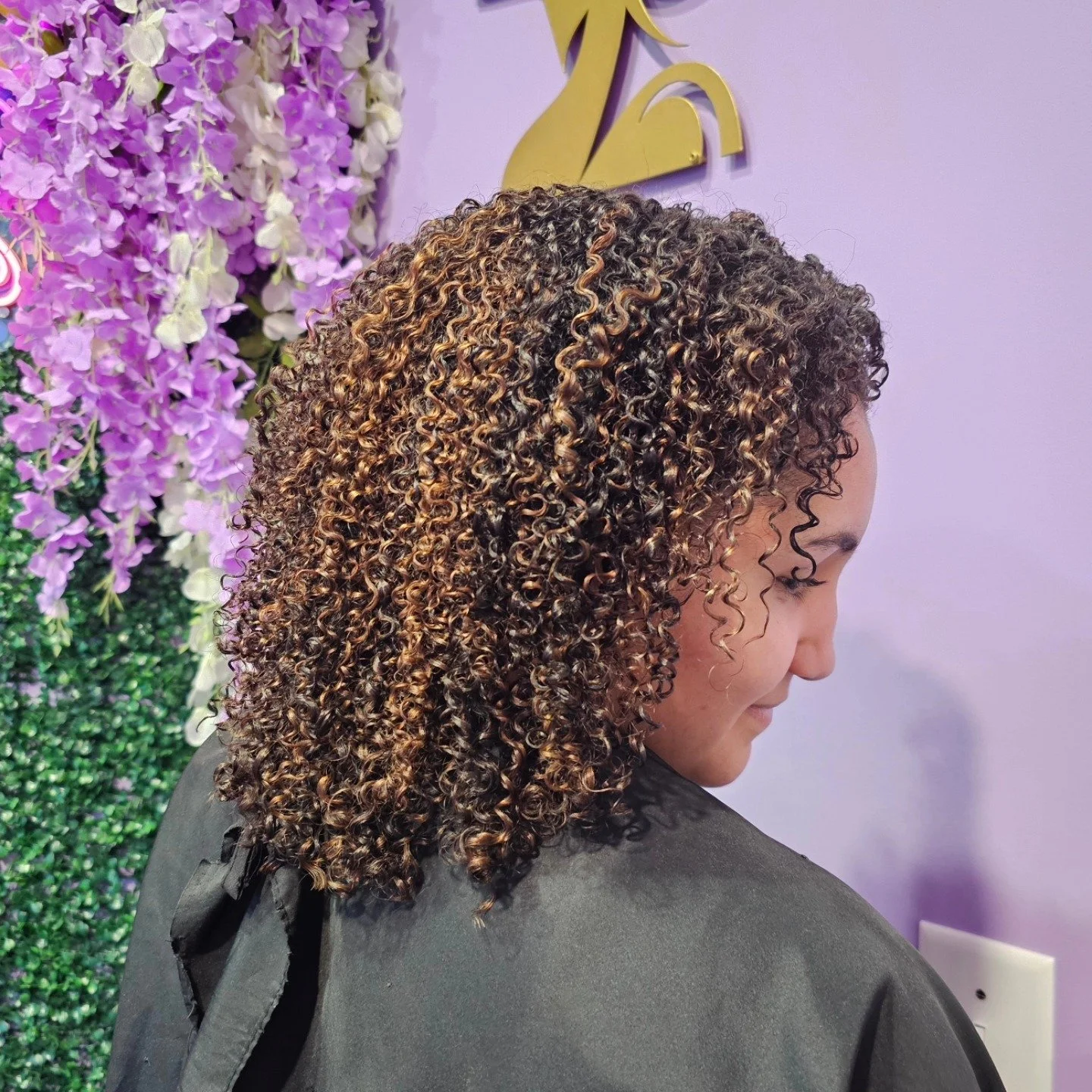 Hand-painted pintura highlights on curly hair shown from the back at Curly Colurz