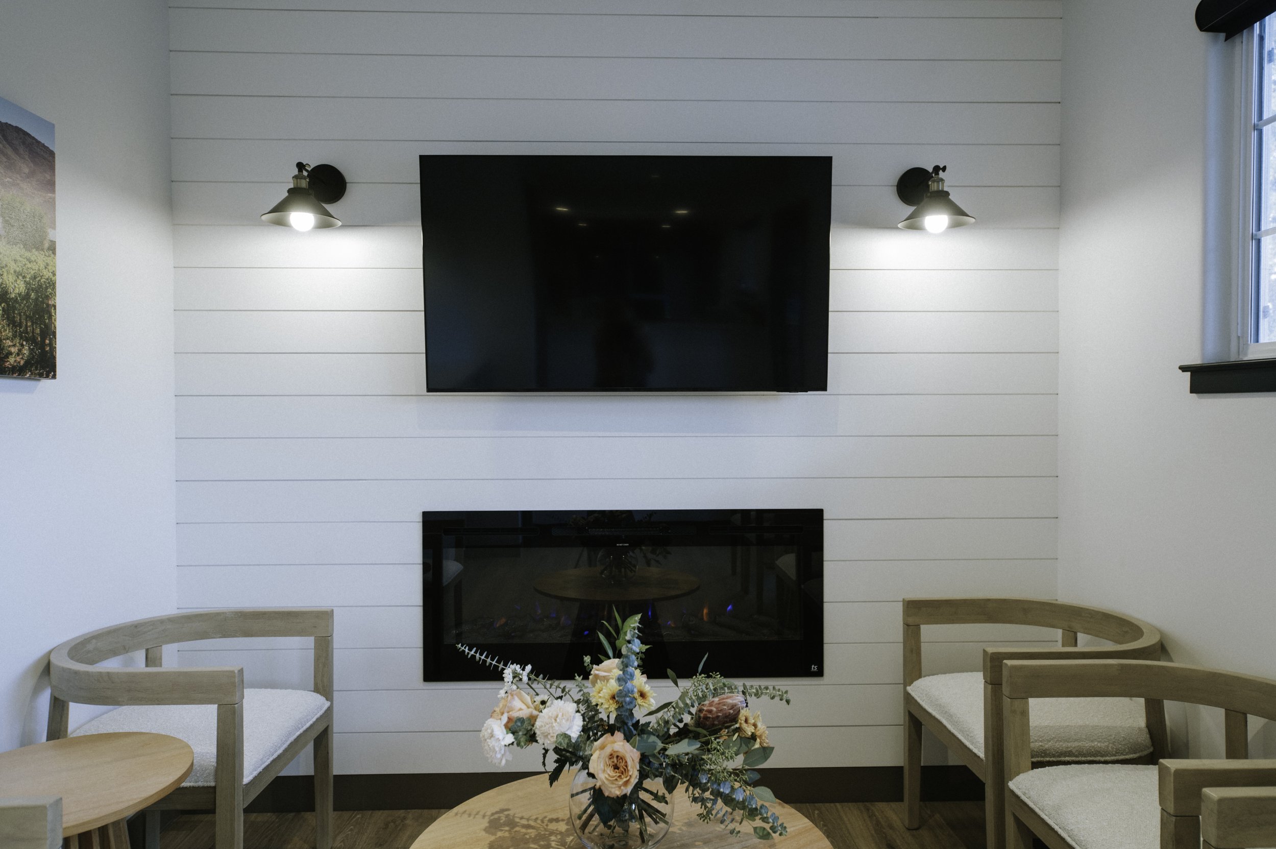 A close up of the nickel gap shiplap siding with farmhouse sconces and a linear fireplace.