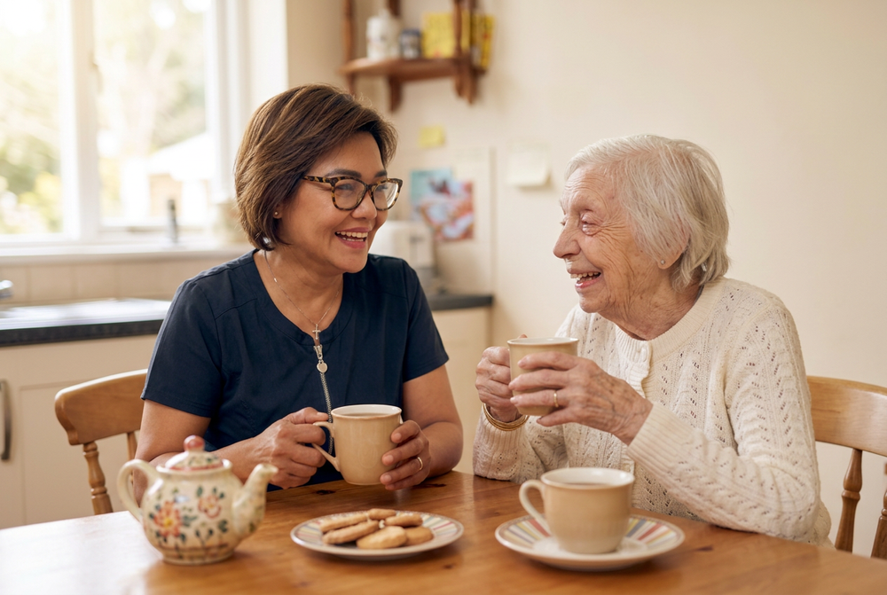 Rosa and Odette laughing over tea at the kitchen table