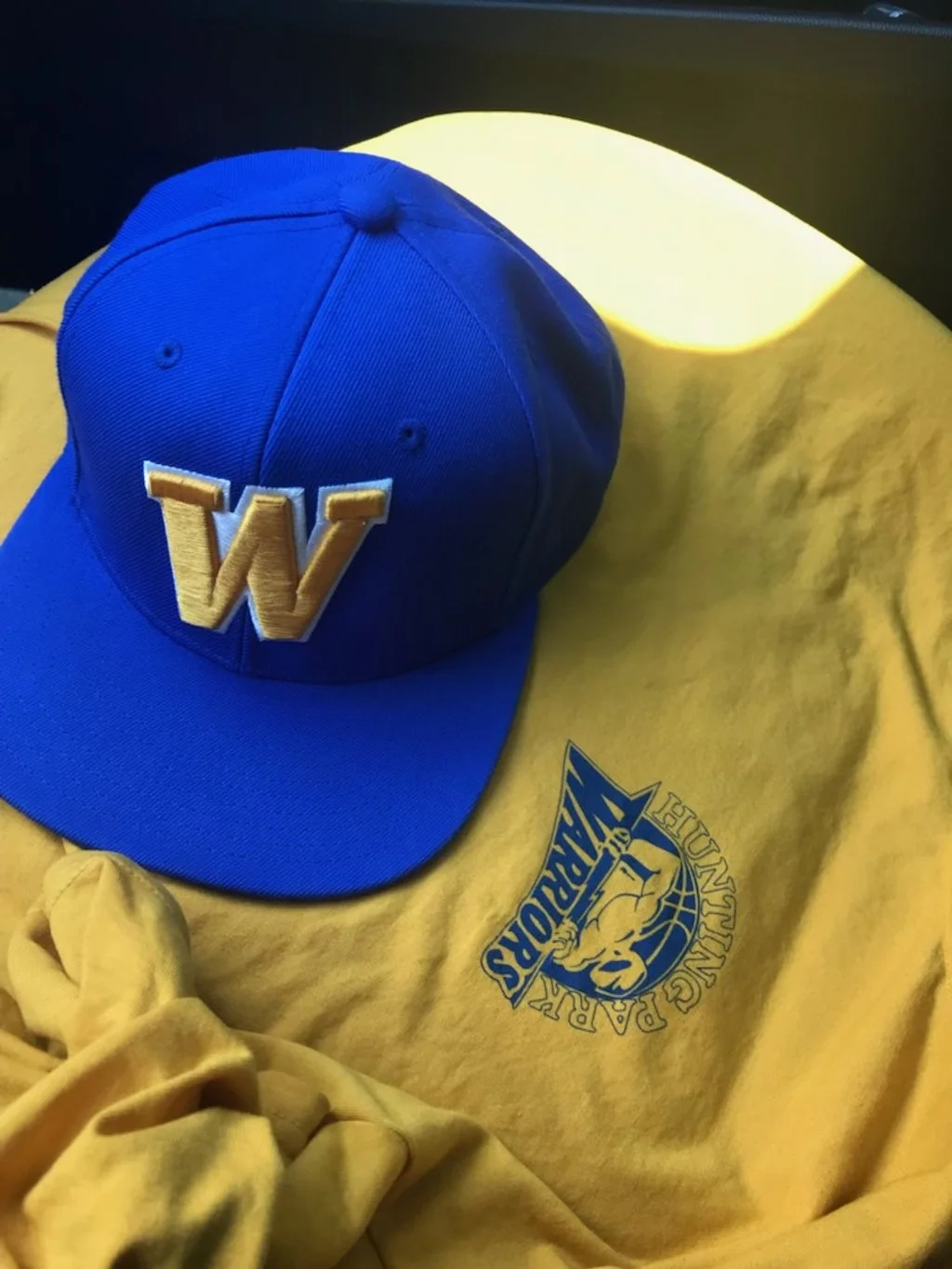 A Blue hat and yellow shirt with the Warriors logo on them. 