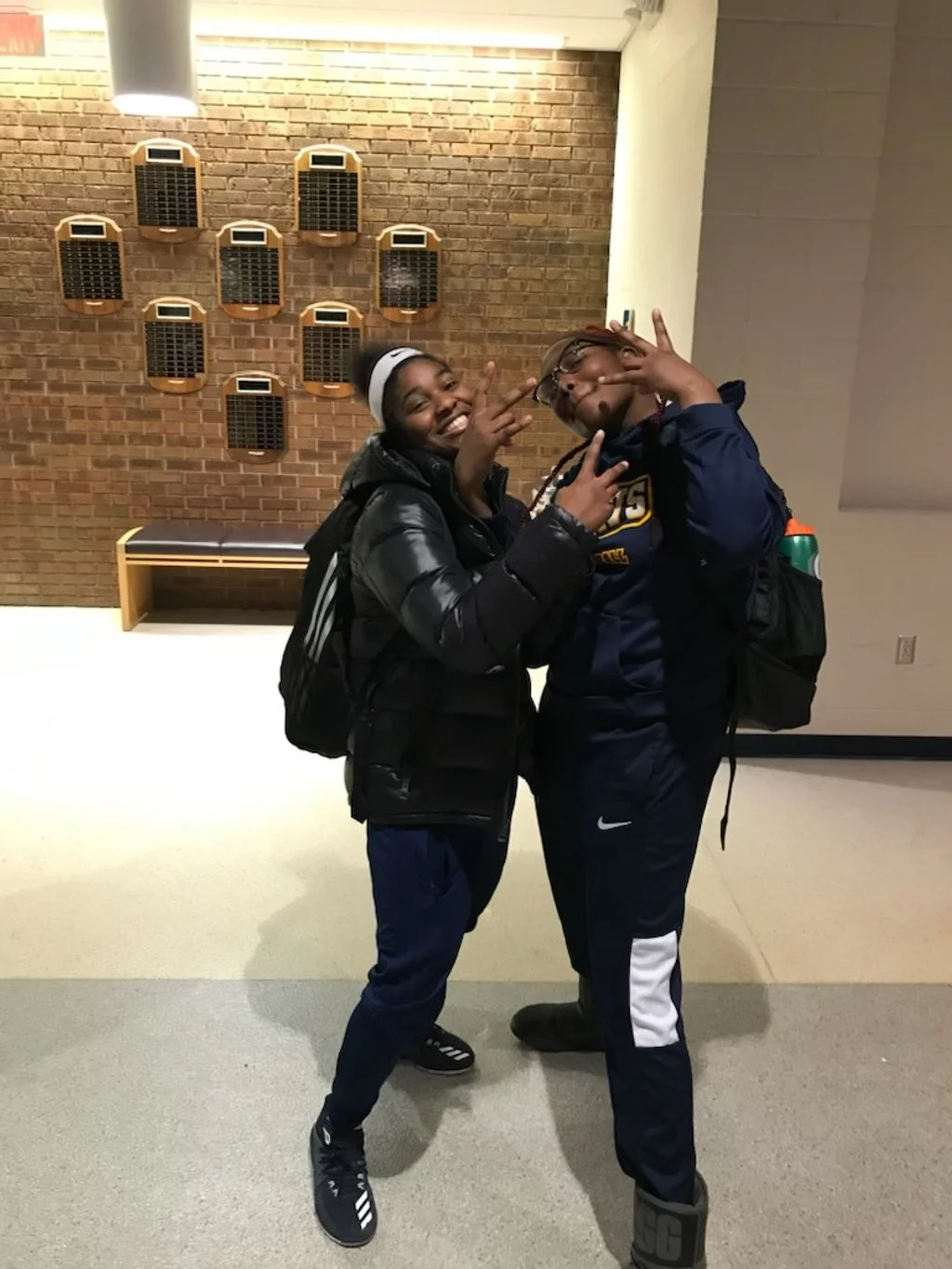 Two young teammates posing for the camera wearing black. 