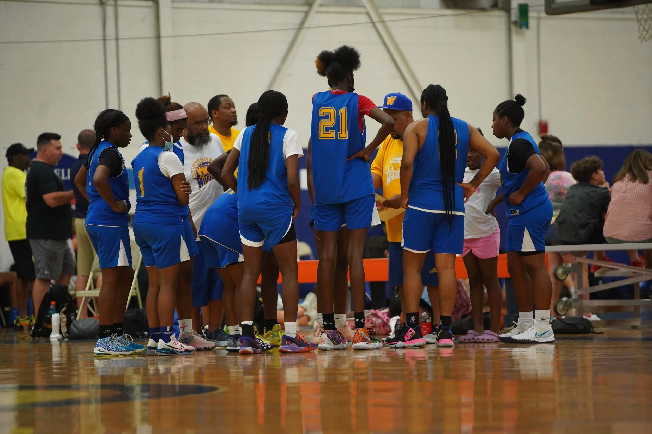 A all female basketball team, wearing blue, yellow and white, with numerous numbers. 