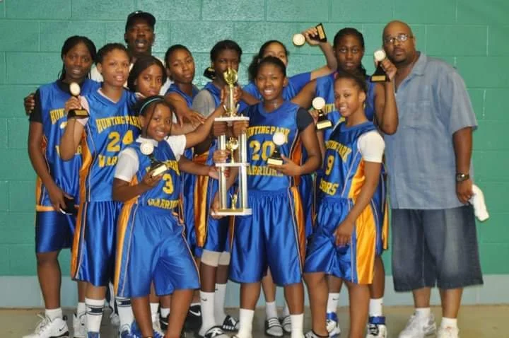 A group of young black females with a trophy. They are wearing white, yellow and blue. 