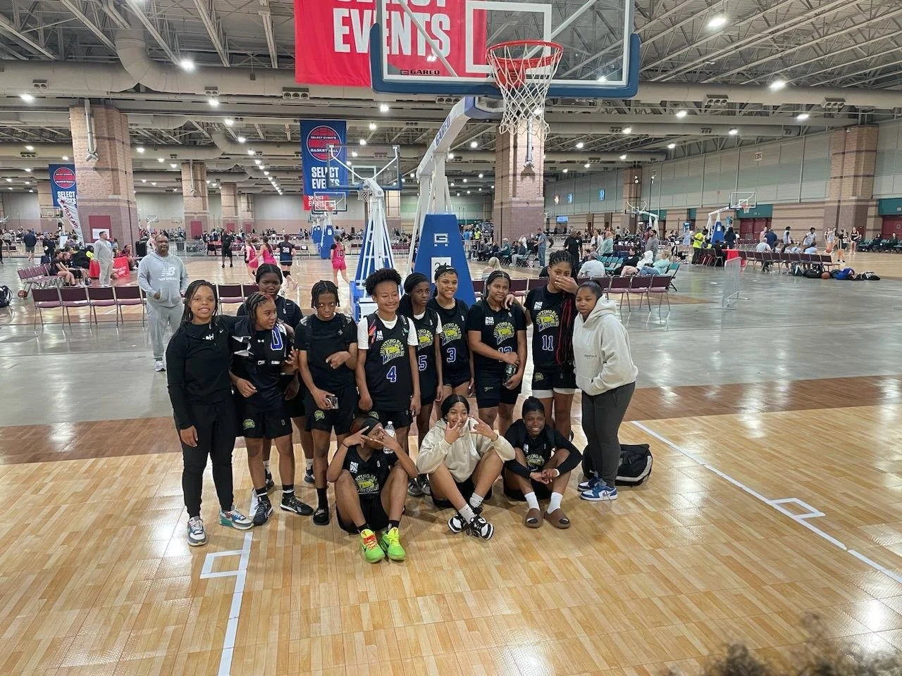 A group of females at a basketball tournament. On a Basketball court.  