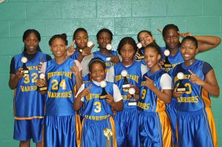 The black young female, smiling at the camera, is holding an individual trophy. 