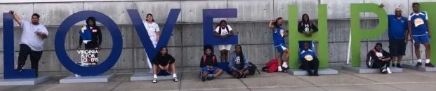 A group of youth sitting on huge letters, that spell out LOVE HP.