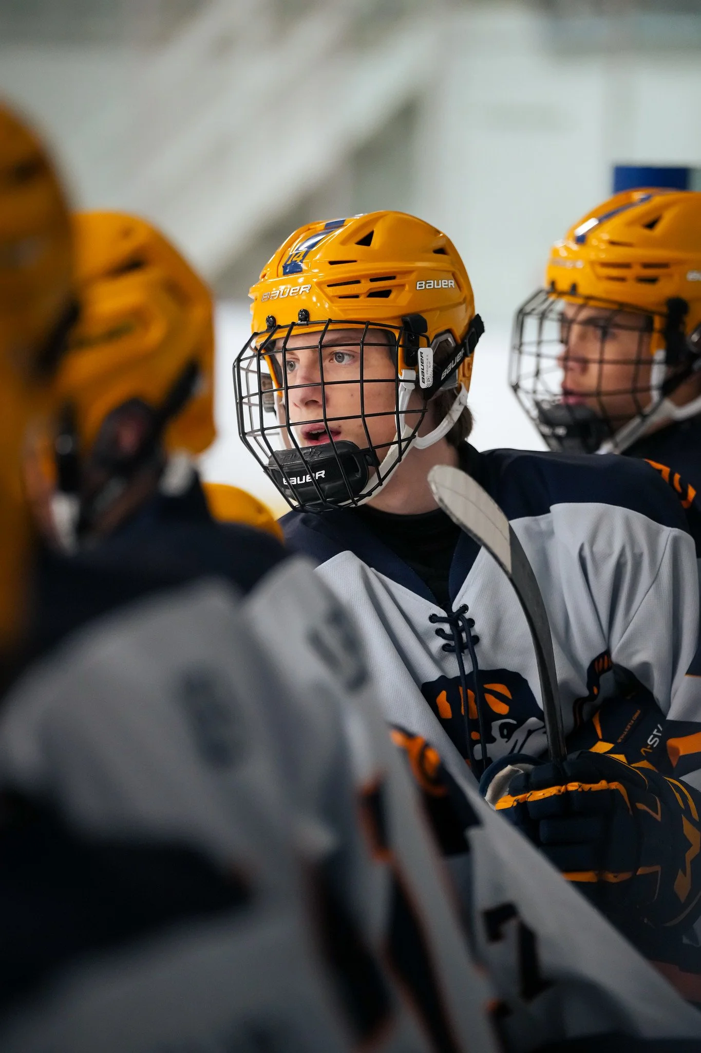 Ice hockey players wearing yellow helmets and black and white jerseys, engaging in a game on an ice rink.