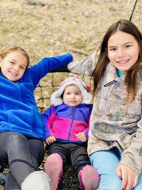 photo of three smiling children of different ages sitting together outdoors in jackets, positioned beneath the title "First Children, First Nations, Child Care Collaborative."