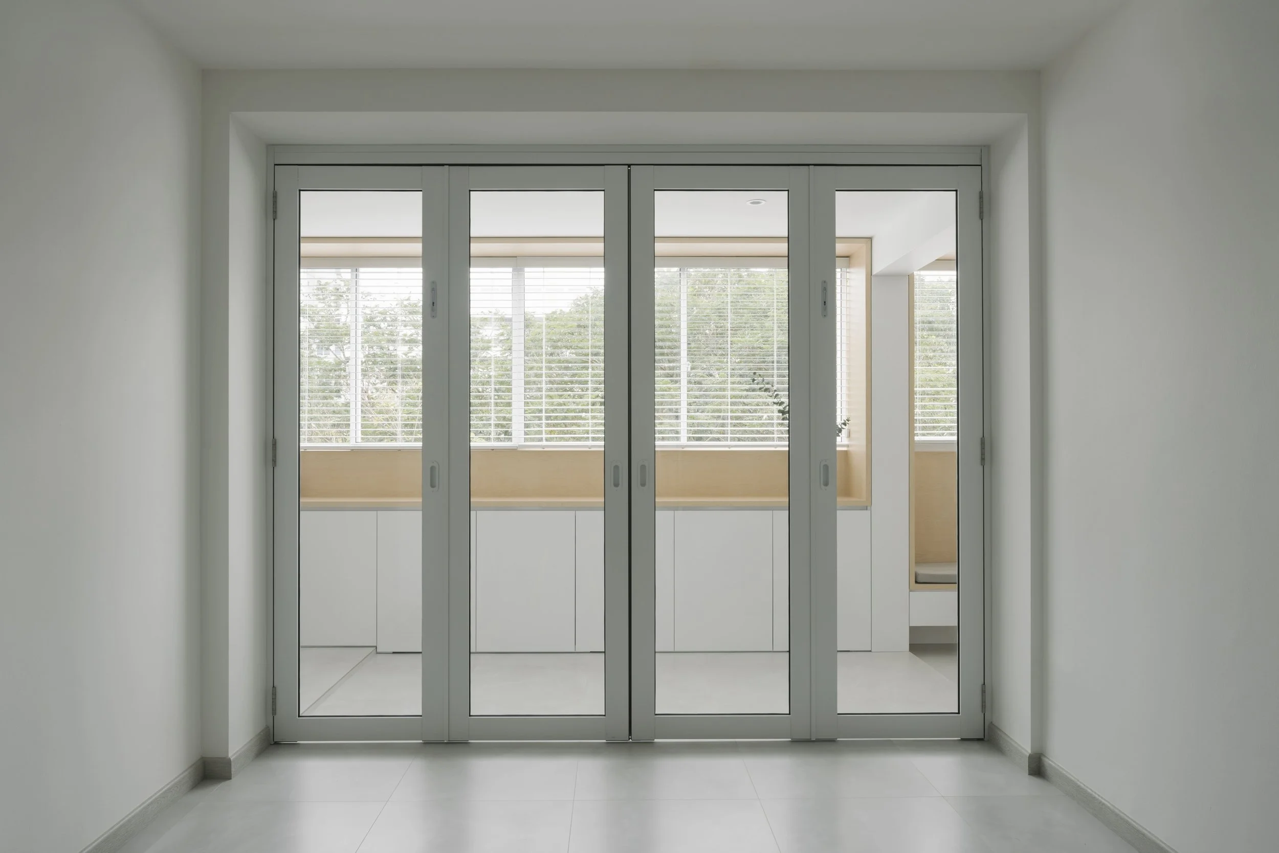 Fully closed aluminium-framed sliding glass doors creating a clean modern partition between two minimalist interior spaces.