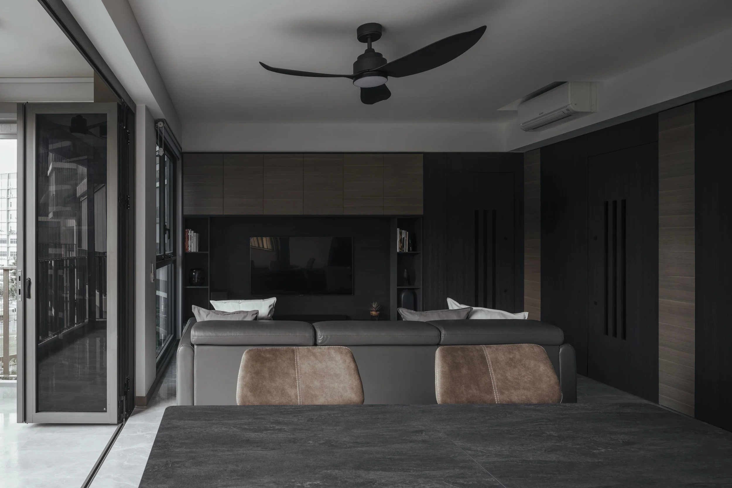 Lite Design Collaborative contemporary Singapore condominium living room featuring dark cabinetry, ceiling fan and open balcony doors.