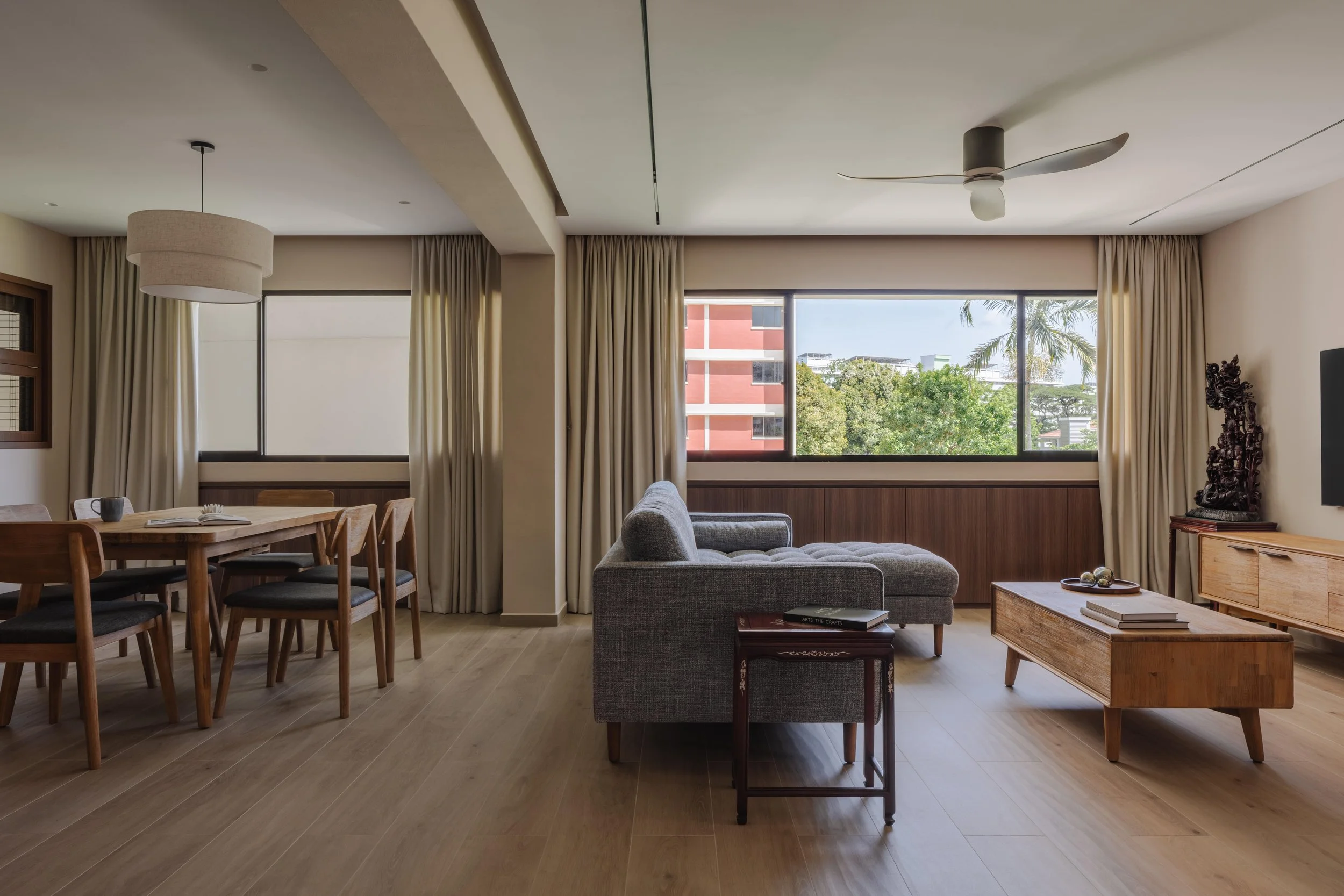 pacious living and dining area in a modern Singapore home featuring warm wood flooring, large windows, and minimalist furniture styling.