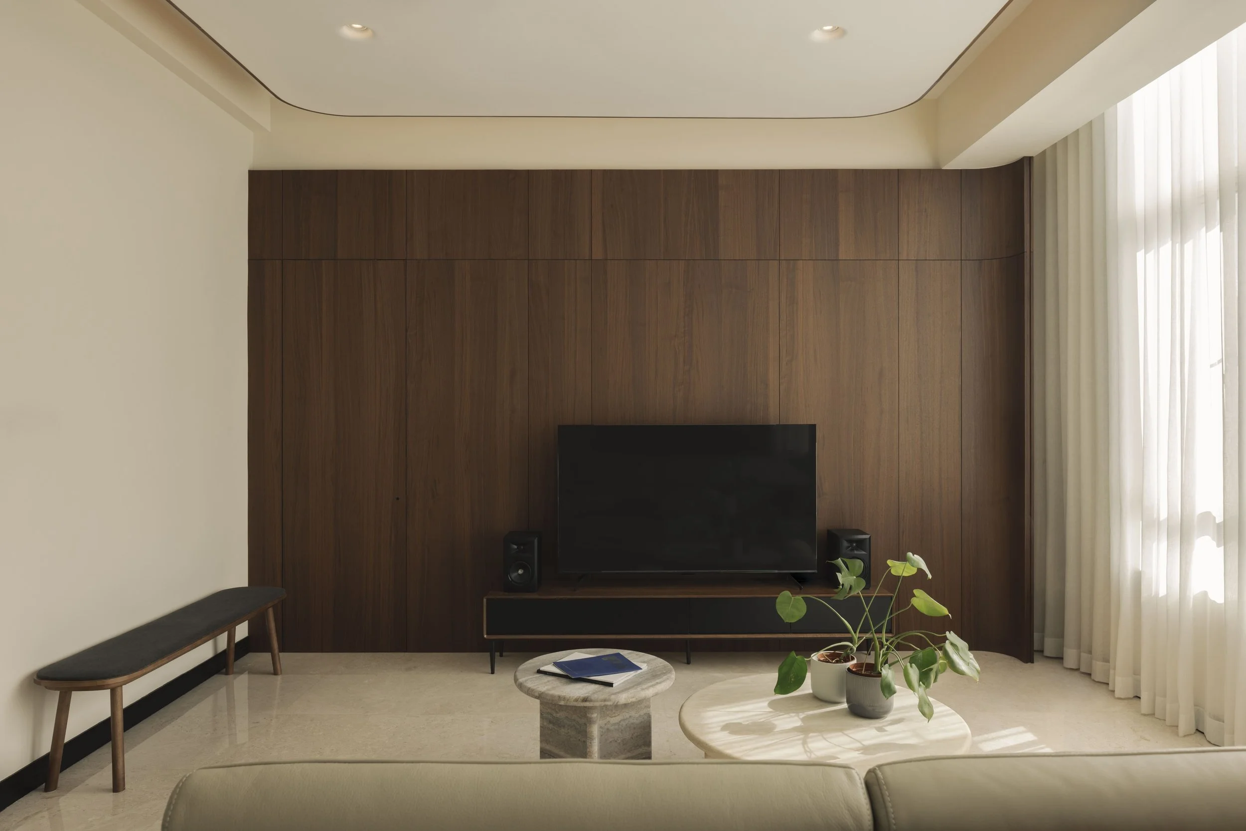 Modern Singapore living room featuring a full-height dark wood feature wall, sleek TV setup, marble coffee table and soft natural lighting.