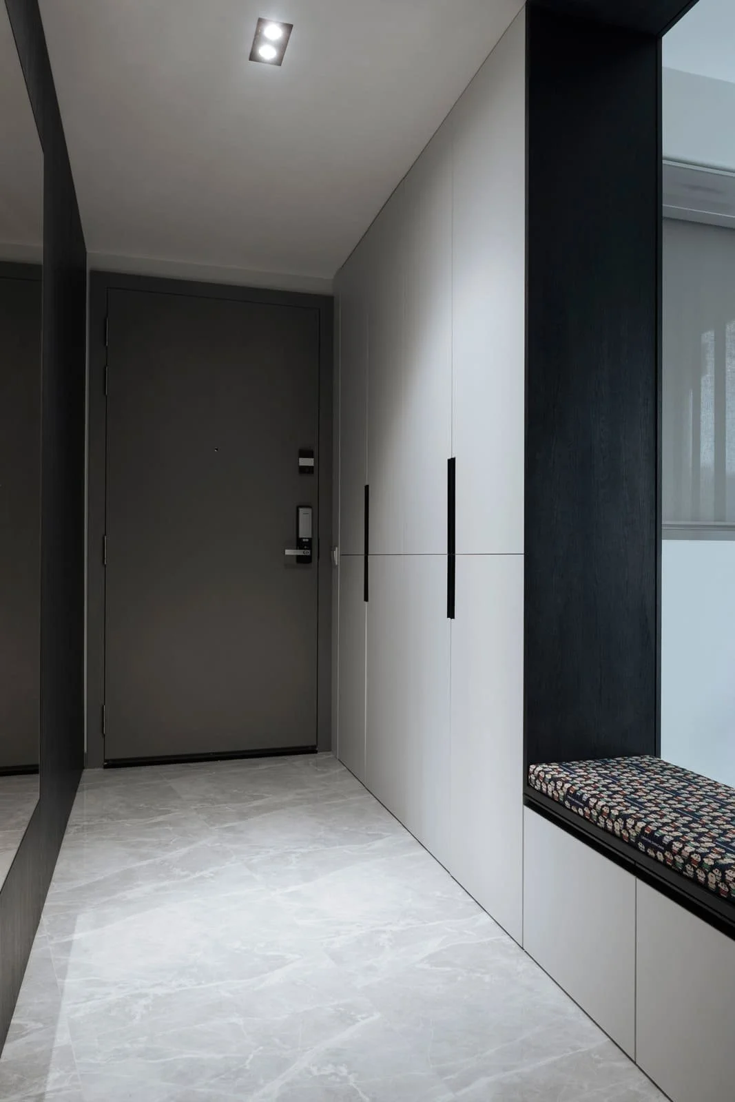 Minimalist Singapore entryway with full-height storage and custom cushioned bench.
