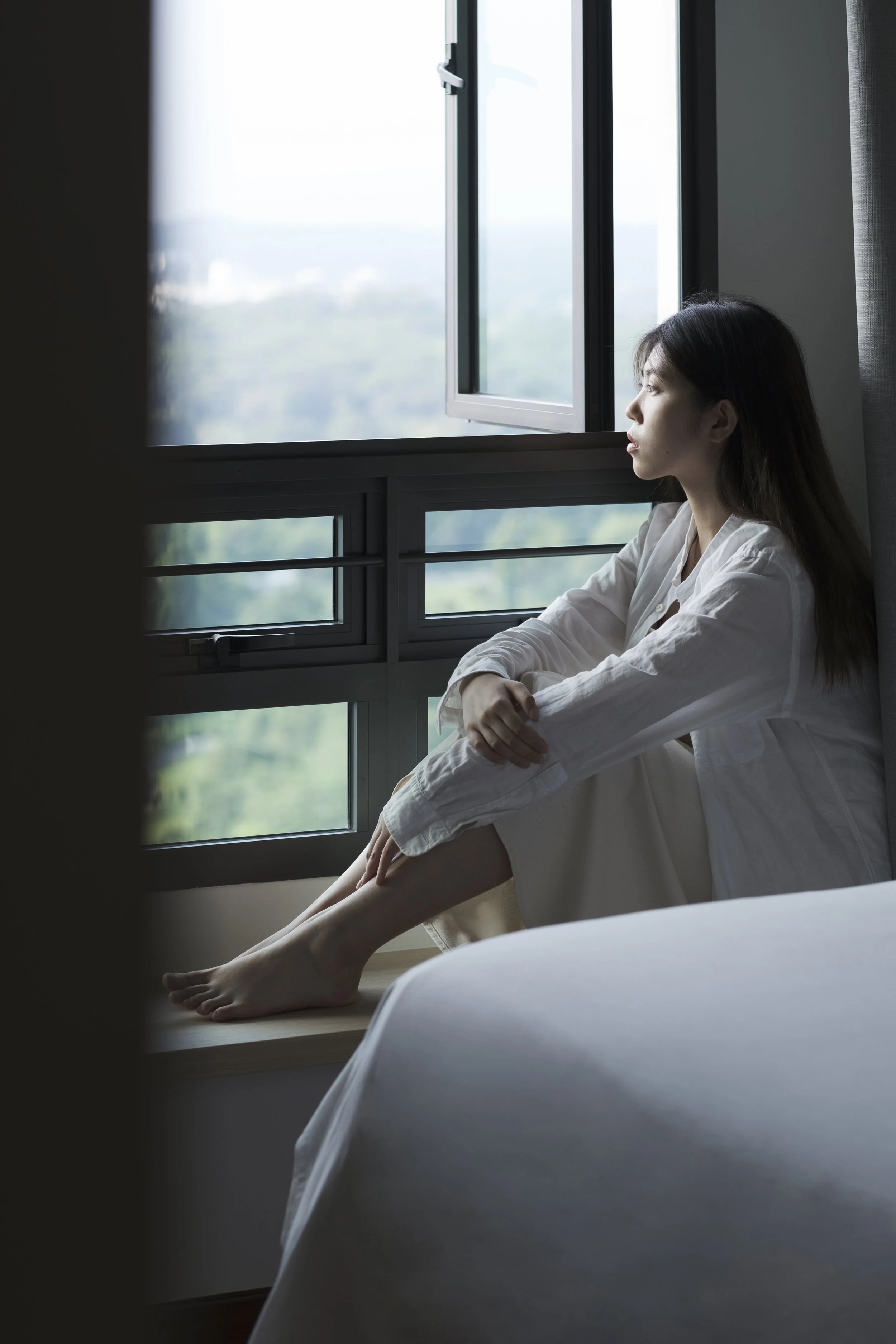 Minimalist Singapore home with a cosy window nook featuring grey curtains and relaxing natural daylight.