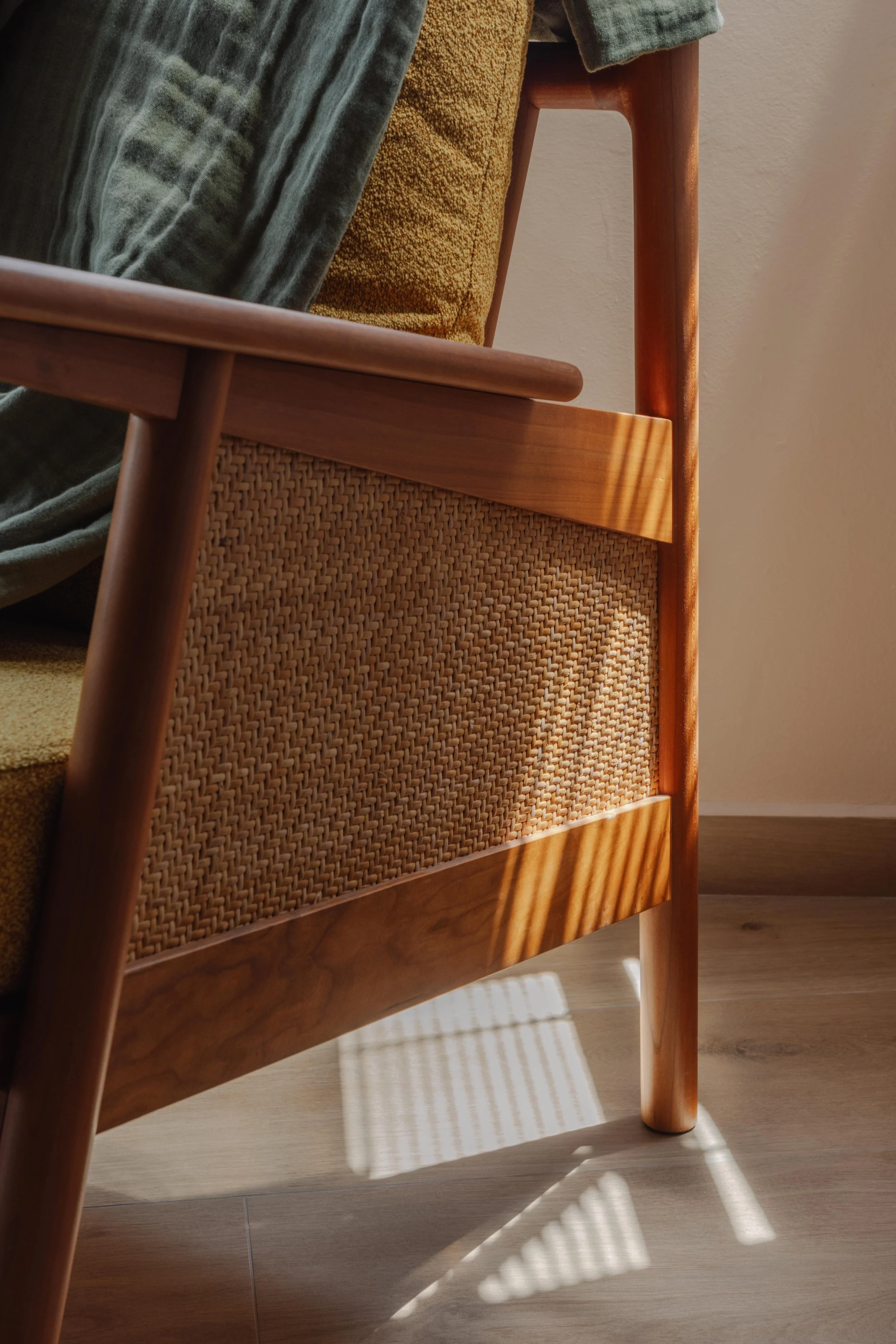 Close-up of a wooden armchair with woven rattan detailing, bathed in natural light in a modern Singapore home.