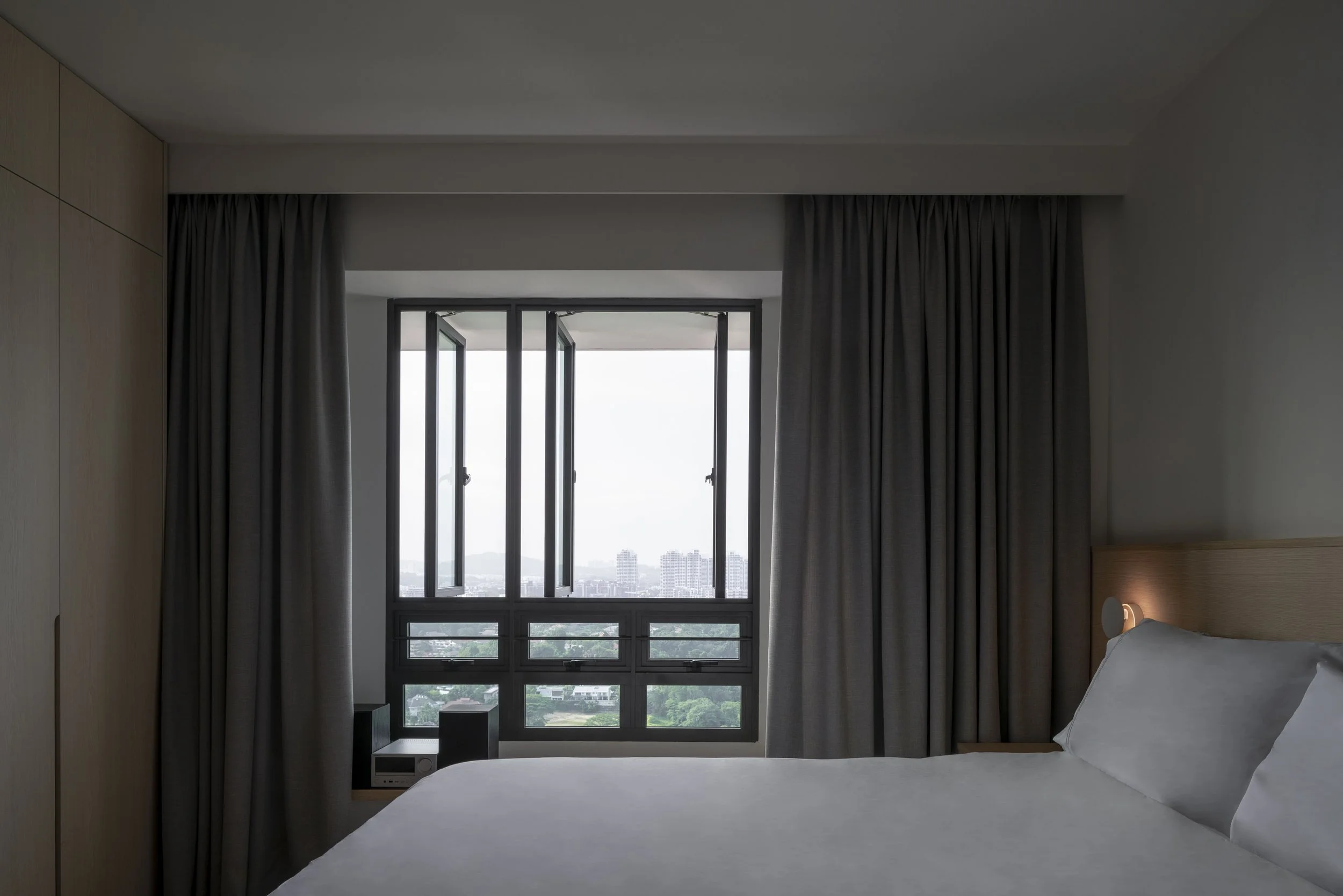 Modern Singapore condo bedroom with full-height windows, grey curtains, and minimalist interior design overlooking city skyline.